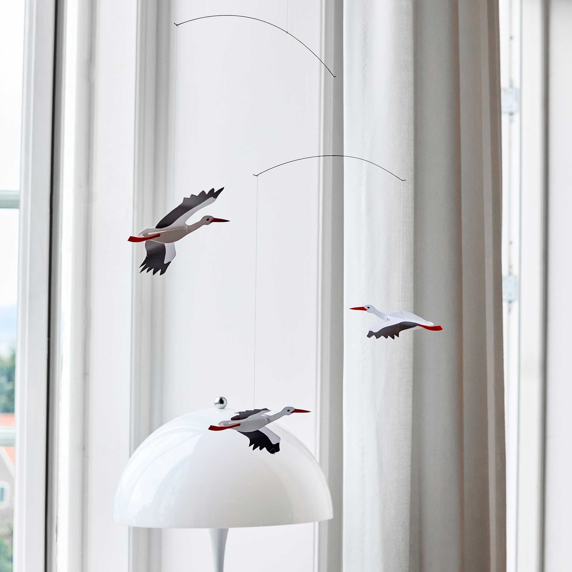 Flensted Mobiles（フレンステッド・モビール）は、1953年創業のデンマーク発・モビール専門ブランド。北欧デザインの文脈に立脚し、造形・質量配分・回転慣性を最適化して、わずかな気流でも自律的に表情を変える構成美を追求します。各パーツは重心とトルクの釣り合いを精密に設計し、静止と運動のあいだを往還する“動く彫刻”として空間に時間軸を付与。代表作「Lucky Storks」から幾何学、鳥類、気球まで多彩で、紙・ステンレス・木材の軽量構造は施工負荷が小さく、住宅・商業・ホスピタリティ・キッズ空間に適合します。現在もデンマーク国内で手作業組立・品質管理を徹底し、視覚ノイズを抑えた運動リズムが集中・鎮静・遊び心をもたらします。北欧インテリアの天井飾りや吊り下げモビールとして、リビング・子供部屋・出産祝いギフトに最適なデンマーク製の正規品です。