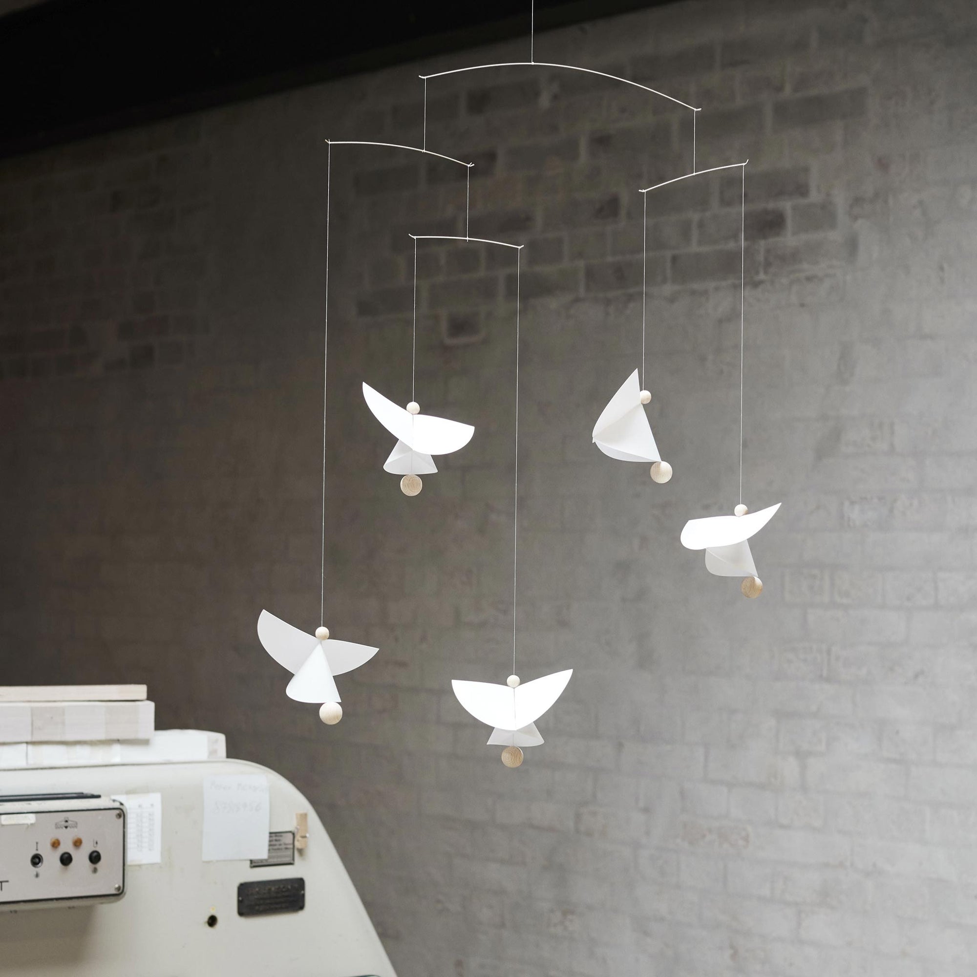 Flensted Mobiles（フレンステッド・モビール）は、1953年創業のデンマーク発・モビール専門ブランド。北欧デザインの文脈に立脚し、造形・質量配分・回転慣性を最適化して、わずかな気流でも自律的に表情を変える構成美を追求します。各パーツは重心とトルクの釣り合いを精密に設計し、静止と運動のあいだを往還する“動く彫刻”として空間に時間軸を付与。代表作「Lucky Storks」から幾何学、鳥類、気球まで多彩で、紙・ステンレス・木材の軽量構造は施工負荷が小さく、住宅・商業・ホスピタリティ・キッズ空間に適合します。現在もデンマーク国内で手作業組立・品質管理を徹底し、視覚ノイズを抑えた運動リズムが集中・鎮静・遊び心をもたらします。北欧インテリアの天井飾りや吊り下げモビールとして、リビング・子供部屋・出産祝いギフトに最適なデンマーク製の正規品です。