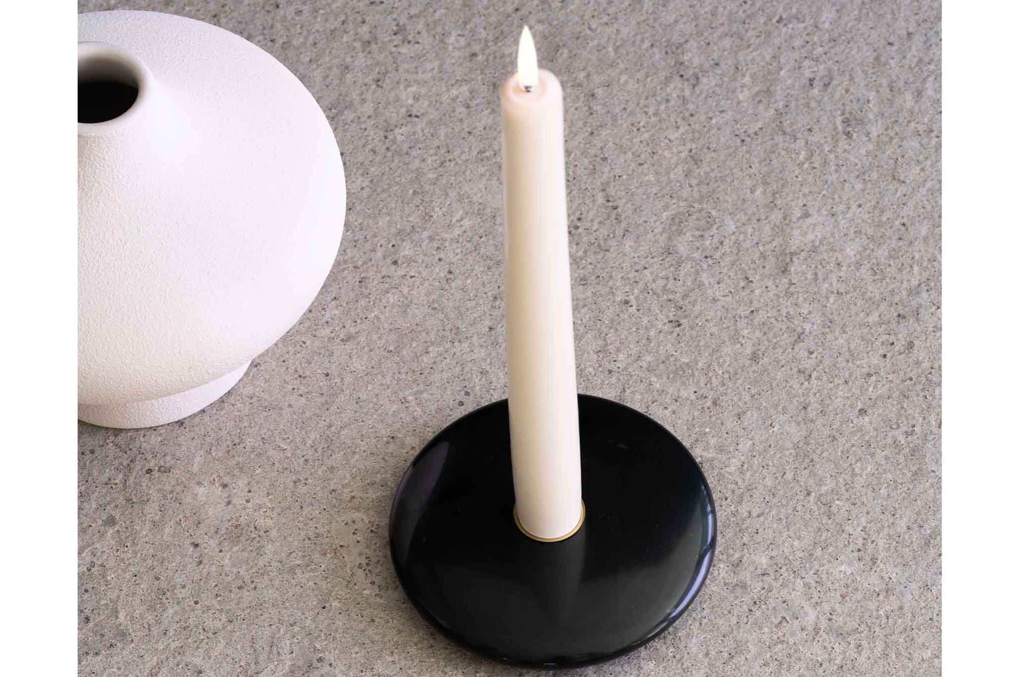 UYUNI Lighting（ウユニ・ライティング）は、デンマークのLEDで本物のキャンドル体験を再現するライティングブランドです。最大の魅力は、特許取得のユニークな「3Dフレーム（炎）」と、目で追ってしまうほど自然なフリッカー表現。灯りの芯が立ち上がるように見える立体的な炎は、見る角度によって表情が変わり、テーブル上のガラス器や壁面に繊細な陰影を落とします。見た目はクラシック、手触りはラグジュアリー、内部機構はイノベーティブ、伝統的なキャンドルの佇まいを、現代のテクノロジーで静かにアップデートしました。外装には本物のワックス（パラフィン加工の表面仕上げ）を用い、日中に置いてあるだけでも上質なオブジェのような存在感。夜は色温度のやさしい光で、北欧らしいhygge（ヒュッゲ）の空気を手軽にまとえます。インテリアの審美眼に応えるプロップとして完成度の高いLEDキャンドルです。