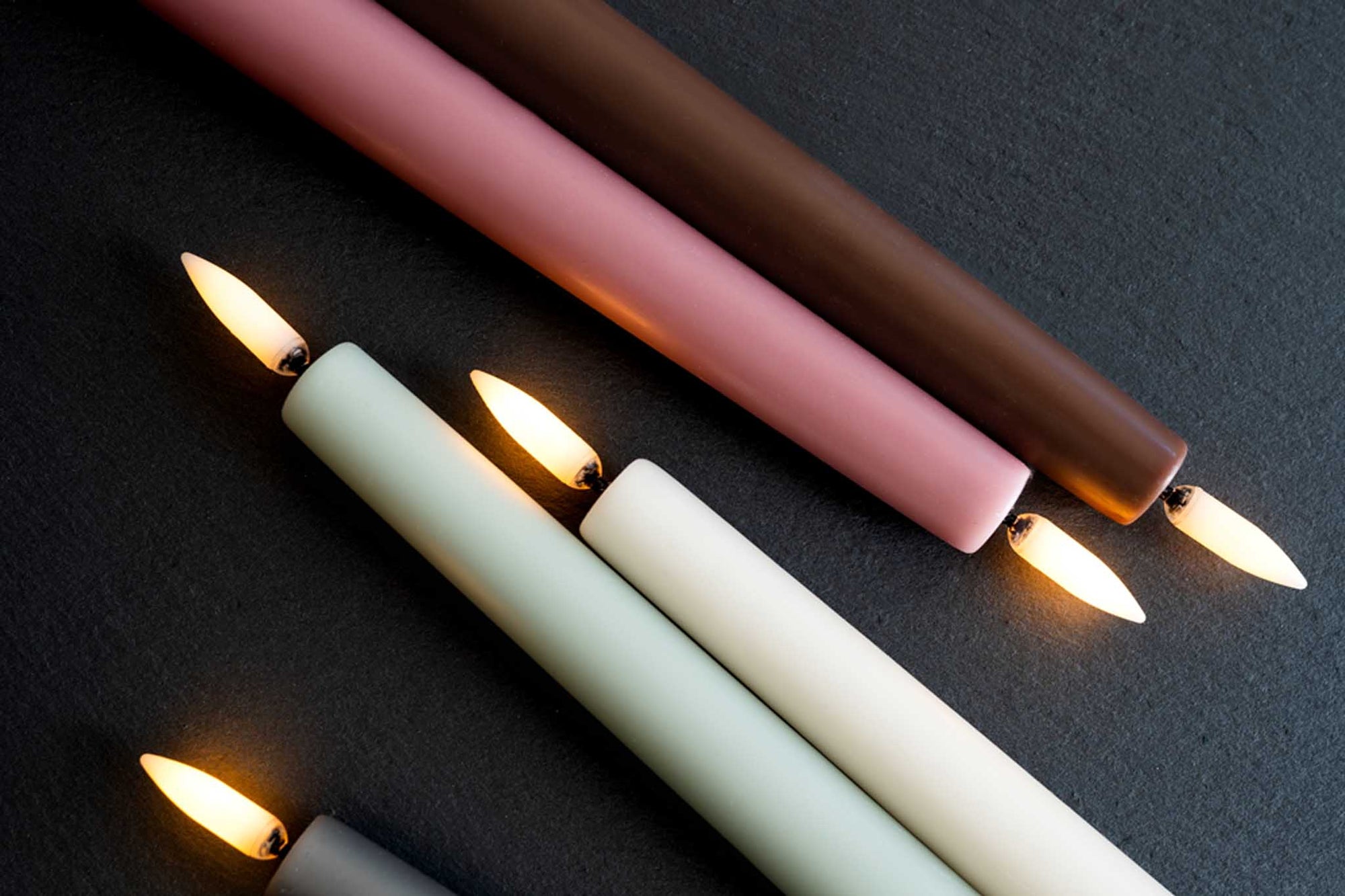 UYUNI Lighting（ウユニ・ライティング）は、デンマークのLEDで本物のキャンドル体験を再現するライティングブランドです。最大の魅力は、特許取得のユニークな「3Dフレーム（炎）」と、目で追ってしまうほど自然なフリッカー表現。灯りの芯が立ち上がるように見える立体的な炎は、見る角度によって表情が変わり、テーブル上のガラス器や壁面に繊細な陰影を落とします。見た目はクラシック、手触りはラグジュアリー、内部機構はイノベーティブ、伝統的なキャンドルの佇まいを、現代のテクノロジーで静かにアップデートしました。外装には本物のワックス（パラフィン加工の表面仕上げ）を用い、日中に置いてあるだけでも上質なオブジェのような存在感。夜は色温度のやさしい光で、北欧らしいhygge（ヒュッゲ）の空気を手軽にまとえます。インテリアの審美眼に応えるプロップとして完成度の高いLEDキャンドルです。