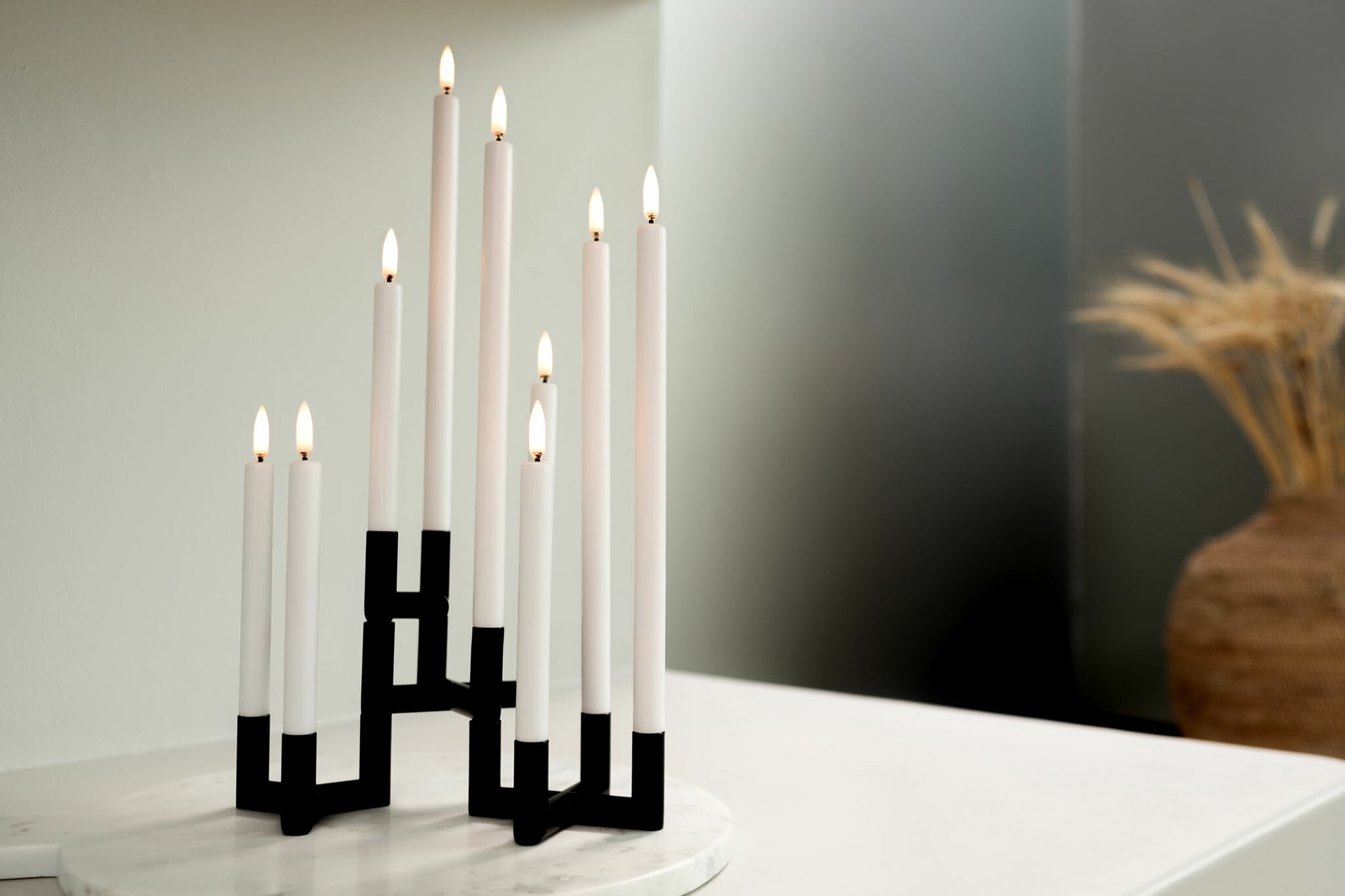 UYUNI Lighting（ウユニ・ライティング）は、デンマークのLEDで本物のキャンドル体験を再現するライティングブランドです。最大の魅力は、特許取得のユニークな「3Dフレーム（炎）」と、目で追ってしまうほど自然なフリッカー表現。灯りの芯が立ち上がるように見える立体的な炎は、見る角度によって表情が変わり、テーブル上のガラス器や壁面に繊細な陰影を落とします。見た目はクラシック、手触りはラグジュアリー、内部機構はイノベーティブ、伝統的なキャンドルの佇まいを、現代のテクノロジーで静かにアップデートしました。外装には本物のワックス（パラフィン加工の表面仕上げ）を用い、日中に置いてあるだけでも上質なオブジェのような存在感。夜は色温度のやさしい光で、北欧らしいhygge（ヒュッゲ）の空気を手軽にまとえます。インテリアの審美眼に応えるプロップとして完成度の高いLEDキャンドルです。