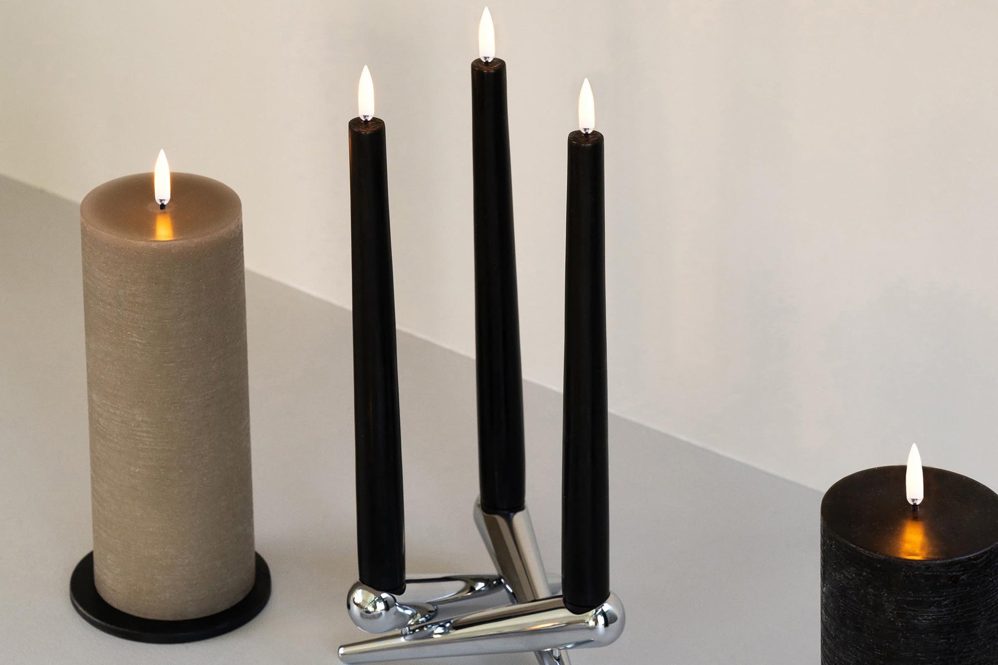 UYUNI Lighting（ウユニ・ライティング）は、デンマークのLEDで本物のキャンドル体験を再現するライティングブランドです。最大の魅力は、特許取得のユニークな「3Dフレーム（炎）」と、目で追ってしまうほど自然なフリッカー表現。灯りの芯が立ち上がるように見える立体的な炎は、見る角度によって表情が変わり、テーブル上のガラス器や壁面に繊細な陰影を落とします。見た目はクラシック、手触りはラグジュアリー、内部機構はイノベーティブ、伝統的なキャンドルの佇まいを、現代のテクノロジーで静かにアップデートしました。外装には本物のワックス（パラフィン加工の表面仕上げ）を用い、日中に置いてあるだけでも上質なオブジェのような存在感。夜は色温度のやさしい光で、北欧らしいhygge（ヒュッゲ）の空気を手軽にまとえます。インテリアの審美眼に応えるプロップとして完成度の高いLEDキャンドルです。