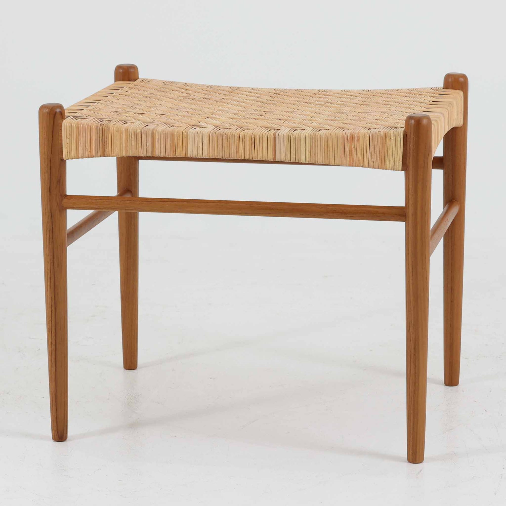 北欧デザインのスツールです。上質なチーク材フレームを丁寧に削り、シャープでスタイリッシュですが、柔らかい表情も持ち合わせたデザインに仕上げています。また、軽量ですが、しっかりとした造りになっています。座面の籐（ラタン）は上質で天然なもので細かい網目状に時間をかけて編み込まれています。使い込むほどにあめ色に変化し馴染んでくるのも天然素材の大きな魅力です。お部屋の片隅にクッションなどを添えて置いておくだけでもおしゃれです。必要なときにすっと出して使えます。複数スタッキングできるのも嬉しいです。
