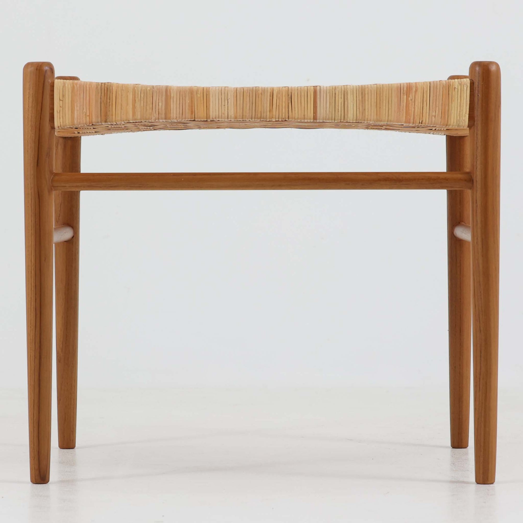 北欧デザインのスツールです。上質なチーク材フレームを丁寧に削り、シャープでスタイリッシュですが、柔らかい表情も持ち合わせたデザインに仕上げています。また、軽量ですが、しっかりとした造りになっています。座面の籐（ラタン）は上質で天然なもので細かい網目状に時間をかけて編み込まれています。使い込むほどにあめ色に変化し馴染んでくるのも天然素材の大きな魅力です。お部屋の片隅にクッションなどを添えて置いておくだけでもおしゃれです。必要なときにすっと出して使えます。複数スタッキングできるのも嬉しいです。