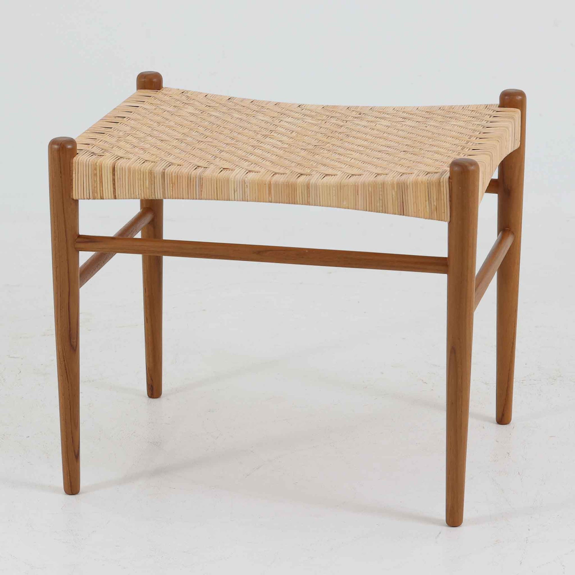北欧デザインのスツールです。上質なチーク材フレームを丁寧に削り、シャープでスタイリッシュですが、柔らかい表情も持ち合わせたデザインに仕上げています。また、軽量ですが、しっかりとした造りになっています。座面の籐（ラタン）は上質で天然なもので細かい網目状に時間をかけて編み込まれています。使い込むほどにあめ色に変化し馴染んでくるのも天然素材の大きな魅力です。お部屋の片隅にクッションなどを添えて置いておくだけでもおしゃれです。必要なときにすっと出して使えます。複数スタッキングできるのも嬉しいです。