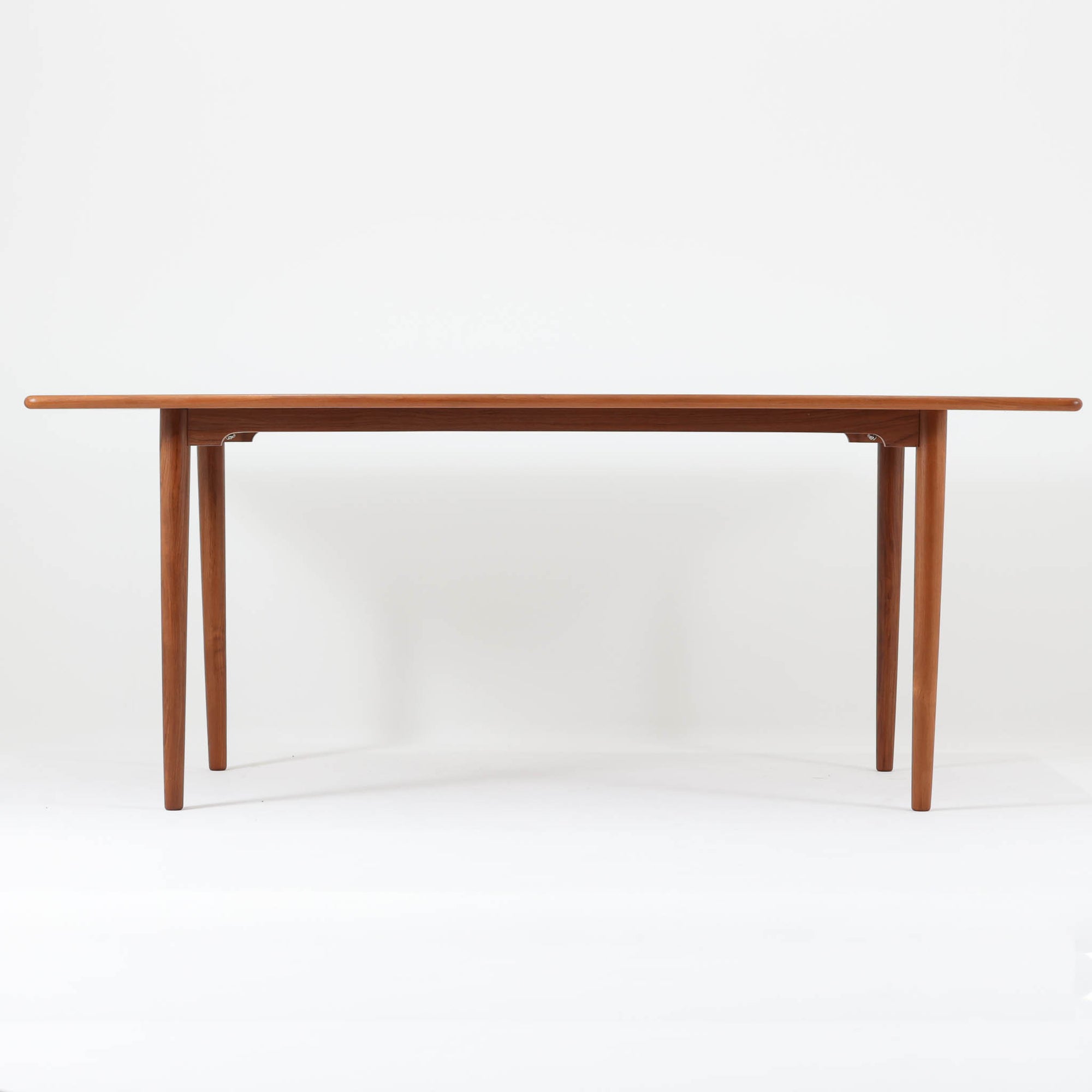 北欧モダンデザイン、180cm幅の大きな６人用ダイニングテーブルです。天板トップには見た目にも美しい上質なチーク突板を使用し、縁には贅沢に無垢材をジョイントしており、耐久力に加え曲線の美しさが際立っています。また、椅子を収納する際に干渉することが多い幕板ですが中央部を浅くすることで、干渉を軽減し、また見た目にも高級感を演出しています。通常安価な材質で仕上げられる幕板や天板裏面にも贅沢にチーク材天然木を使用しております。脚のポジションはやや内側にセットされスタイリッシュなデザインにも仕上がっています。
