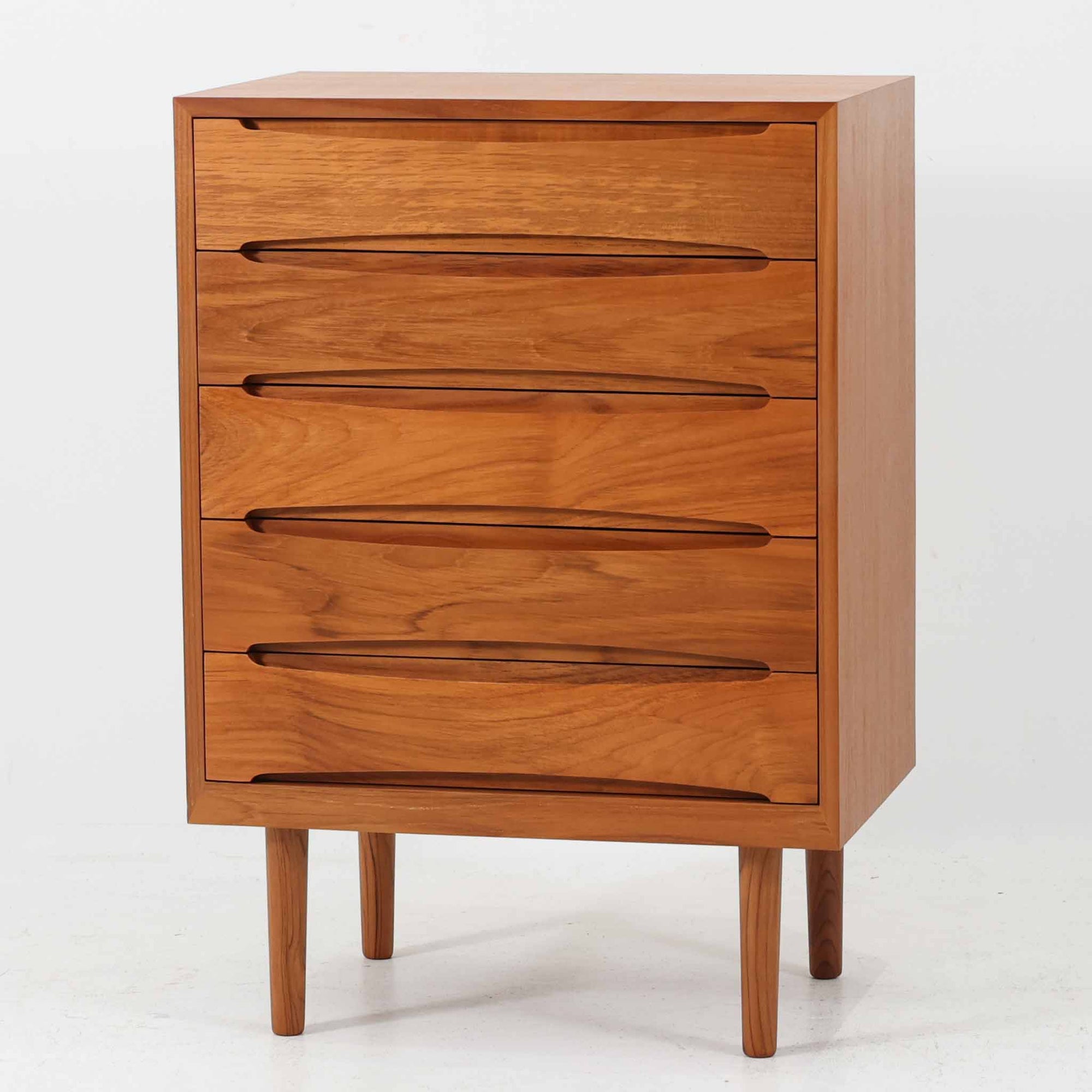 北欧モダンスタイルの少し小ぶりな5段ハイチェストです。取っ手を葉っぱの形に削りだしているのが特徴的なデザインです。使い勝手も良好で、収納時見た目にも大変上品で美しい雰囲気があります。素材は脚も含め全てチーク材を使用しており、美しい暖かな風合いの木目が心地よさを演出します。少し小さめなのがお部屋を圧迫することもなくおしゃれに演出することが可能です。
