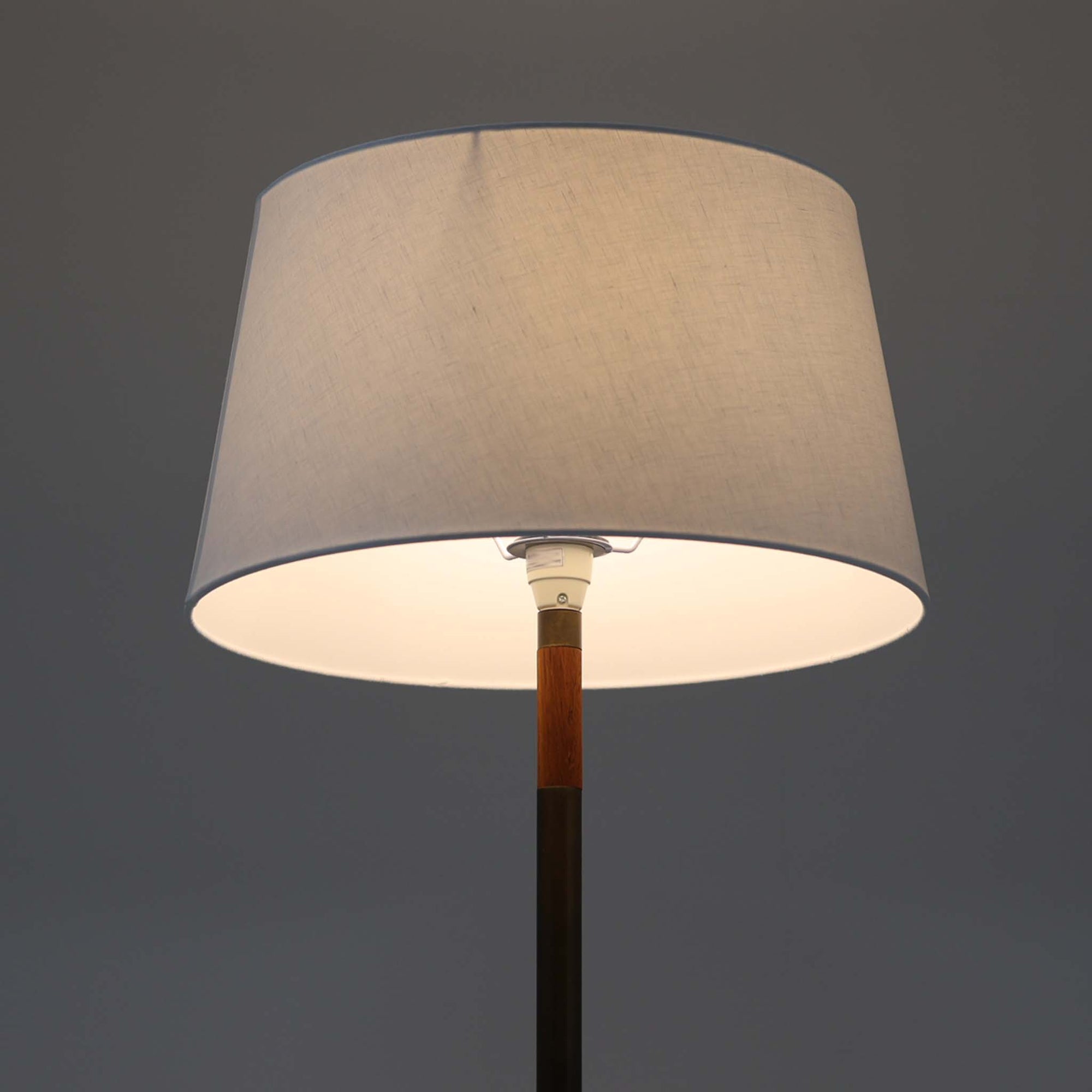 Jo HammerborgがFog &amp; Morupのために手がけた「Monolit」は、真鍮のシャフトにチーク材のアクセントを加えたミニマルで洗練されたフロアランプです。高さ164cmの堂々たるプロポーションに、Y字型の真鍮ベースが独自の存在感を放ち、リネンシェードを通した柔らかな光が空間に落ち着きを与えます。素材のコントラストと構造美が際立つ一台は、北欧ビンテージ照明の中でも特に希少な逸品といえるでしょう。