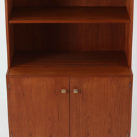 デンマークのHorsens Mobelfabrik社によるディスプレイシェルフは、温かみあるチーク材を使用した端正な佇まいが魅力の一台です。上段には可動棚が4枚備わっており、書籍やオブジェなどのディスプレイに最適です。下段は観音開きの収納扉付きで、見せる収納と隠す収納を両立。すっきりとした脚部構造と洗練された金属取手がアクセントとなり、北欧らしい実用性と美しさを兼ね備えたビンテージ家具です。