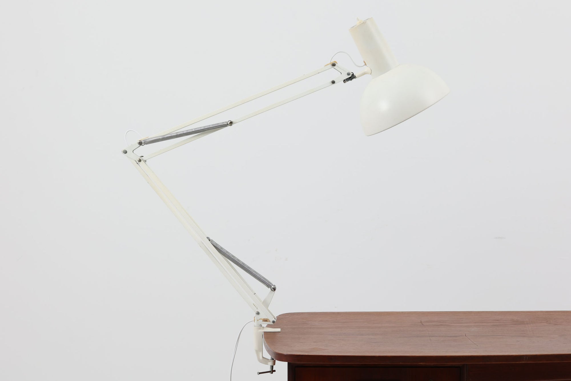 デンマークより買い付けたLouis Poulsen社製のデスクランプです。現行品では販売されていない希少なモデルで、シンプルながら機能的なデザインが特徴です。クランプタイプのため、置く場所を選ばず使用可能。最大板厚5cmまでの場所に取り付けることができるため、デスクやテーブルにしっかり固定してお使いいただけます。アーム部分は可動式で、光の角度を自由に調整できる設計になっており、デスクワークや読書、細かい作業にも最適です。ビンテージ品ならではの風合いが魅力的で、使い込まれたスチールの質感が独特の味わいを醸し出しています。