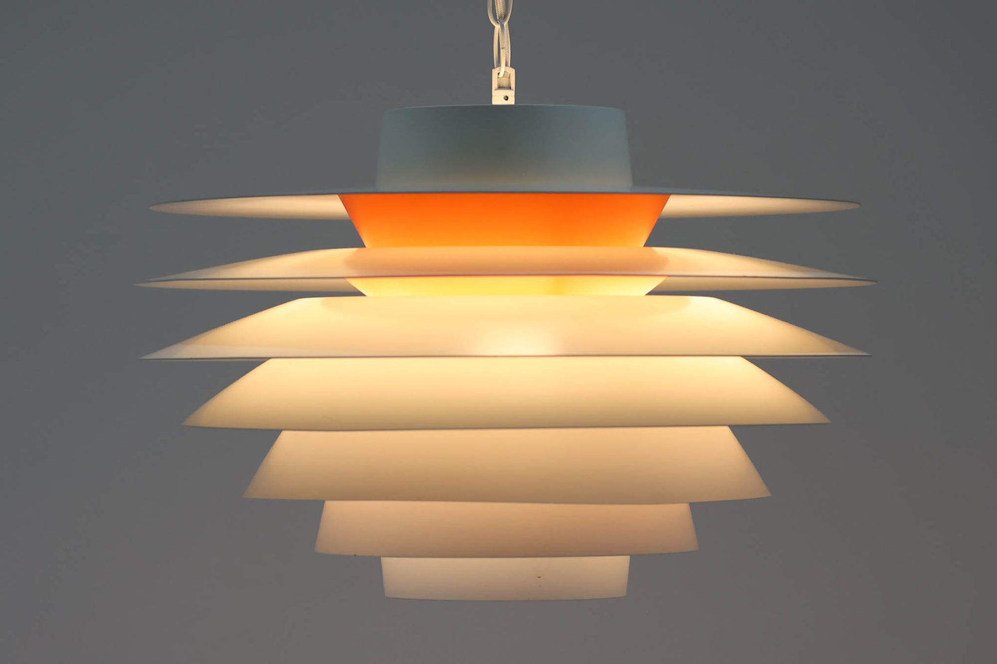 デンマークより買い付けた、Svend middelboe（スヴェン・ミデルボー）デザインの「Velona（ヴェローナ）」です。角度の異なる複数のシェードが、見た目だけでなく美しい光のグラデーションを演出します。北欧照明を代表するデザインで、2020年にLYFAによって復刻されましたが、こちらはNordisk Solar社で生産された希少な当時のモデルで、中心部がオレンジ色に塗装されています。また、直径が48cmと大きく存在感がございます。なお、現行品は内部が白色塗装となっており、現行品の定価は為替レートにより変動しますが、おおよそ20〜25万円程度です