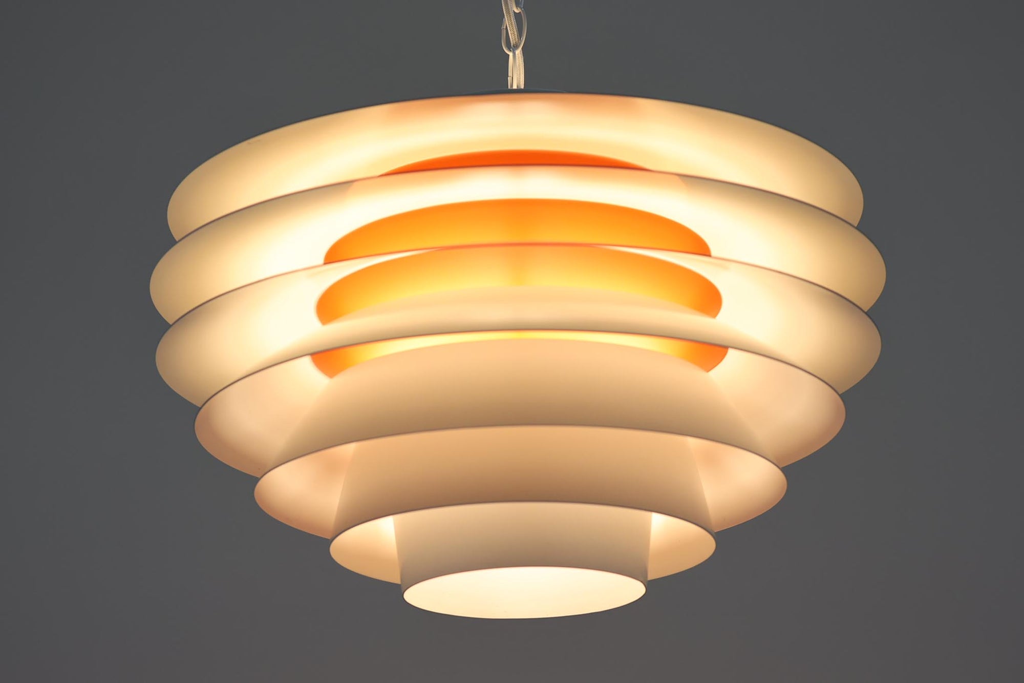 デンマークより買い付けた、Svend middelboe（スヴェン・ミデルボー）デザインの「Velona（ヴェローナ）」です。角度の異なる複数のシェードが、見た目だけでなく美しい光のグラデーションを演出します。北欧照明を代表するデザインで、2020年にLYFAによって復刻されましたが、こちらはNordisk Solar社で生産された希少な当時のモデルで、中心部がオレンジ色に塗装されています。現行品は内部が白色塗装となっており、現行品の定価はレートにより変動しますが、おおよそ20〜25万円程度です