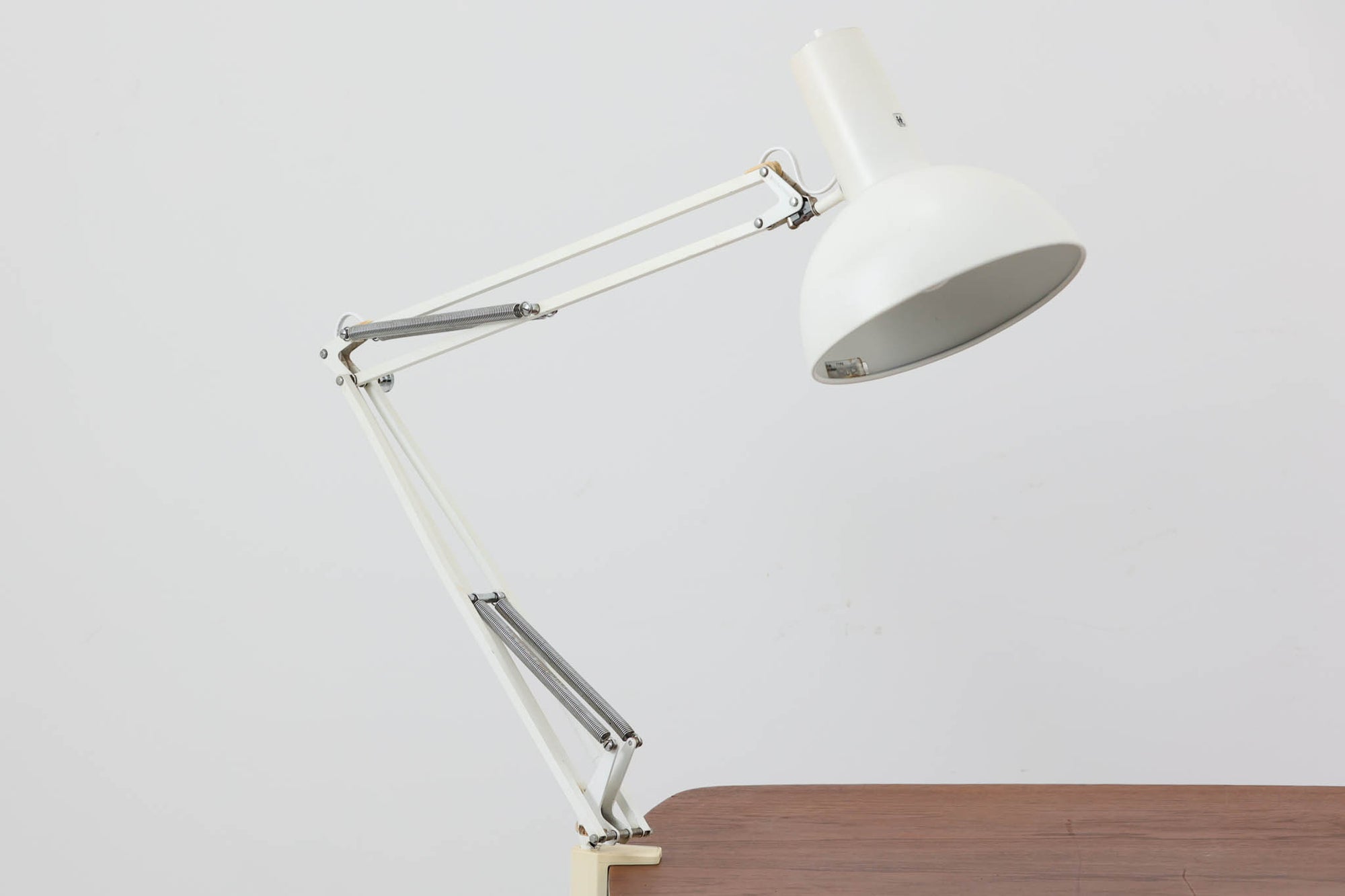 デンマークより買い付けたLouis Poulsen社製のデスクランプです。現行品では販売されていない希少なモデルで、シンプルながら機能的なデザインが特徴です。クランプタイプのため、置く場所を選ばず使用可能。最大板厚5cmまでの場所に取り付けることができるため、デスクやテーブルにしっかり固定してお使いいただけます。アーム部分は可動式で、光の角度を自由に調整できる設計になっており、デスクワークや読書、細かい作業にも最適です。ビンテージ品ならではの風合いが魅力的で、使い込まれたスチールの質感が独特の味わいを醸し出しています。
