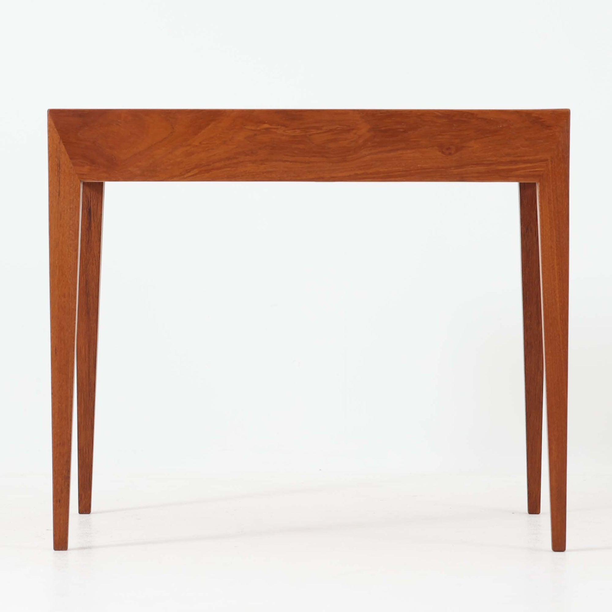 Severin Hansen Jr.によってデザインされ、Haslev社より製造されたこちらのサイドテーブルは、引き出しを備えた実用性と、シャープな面取りが際立つ意匠性を兼ね備えた一台です。チーク材の温もりある木目と、先細りのテーパードレッグが軽やかな印象を与え、繊細なジョイント仕上げからは北欧ビンテージ家具ならではの高いクラフトマンシップが感じられます。ベッドサイドやソファ横のアクセントとしてもおすすめです。