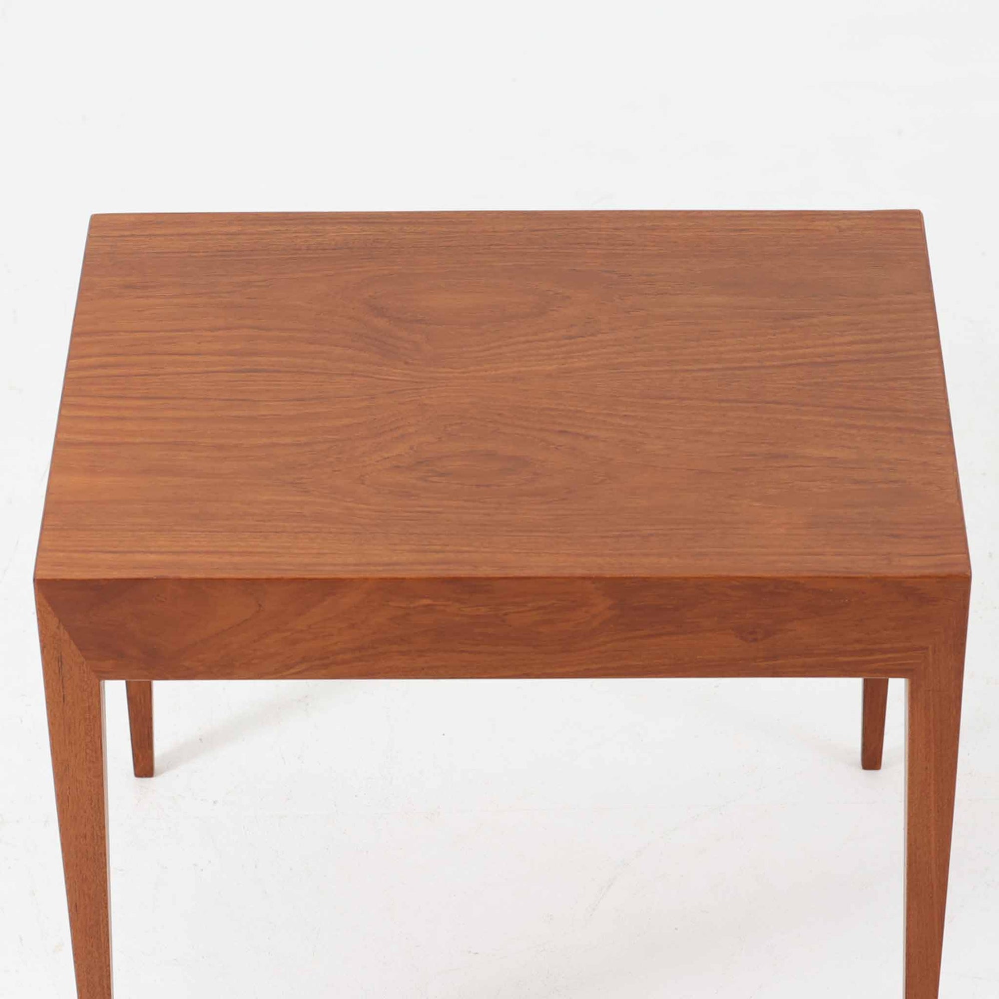 Severin Hansen Jr.によってデザインされ、Haslev社より製造されたこちらのサイドテーブルは、引き出しを備えた実用性と、シャープな面取りが際立つ意匠性を兼ね備えた一台です。チーク材の温もりある木目と、先細りのテーパードレッグが軽やかな印象を与え、繊細なジョイント仕上げからは北欧ビンテージ家具ならではの高いクラフトマンシップが感じられます。ベッドサイドやソファ横のアクセントとしてもおすすめです。