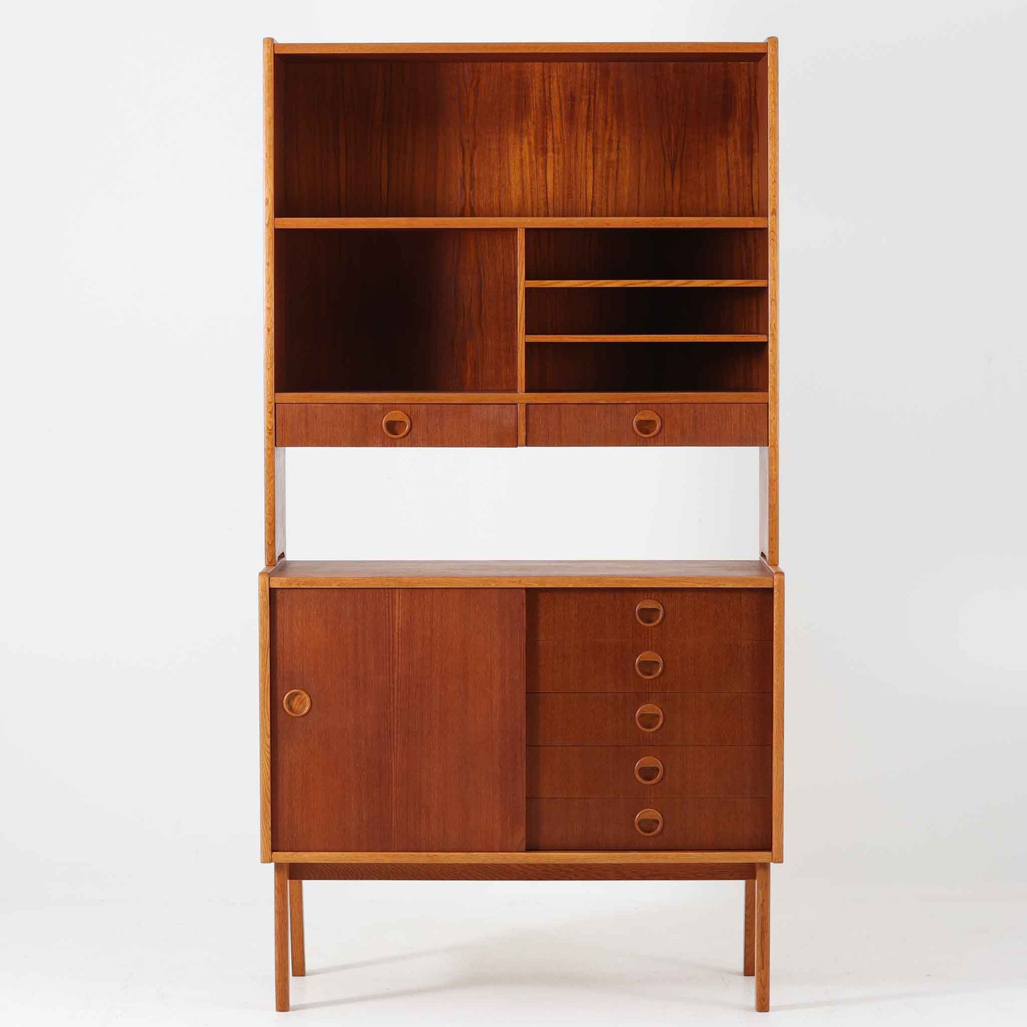 チーク材とオーク材を組み合わせたこちらのオープンシェルフは、スウェーデン製の北欧ビンテージ品で、幅85cmのコンパクトなサイズ感ながらも、引き出しや仕切り棚、スライド扉など多彩な収納機能を備えた実用的な一台です。温かみのある木の風合いと丸型の取手が、柔らかな印象を与えつつ、細部にまで配慮された職人技が感じられ、リビングや書斎の収納棚としてはもちろん、お気に入りの器や小物のディスプレイにも適しています。