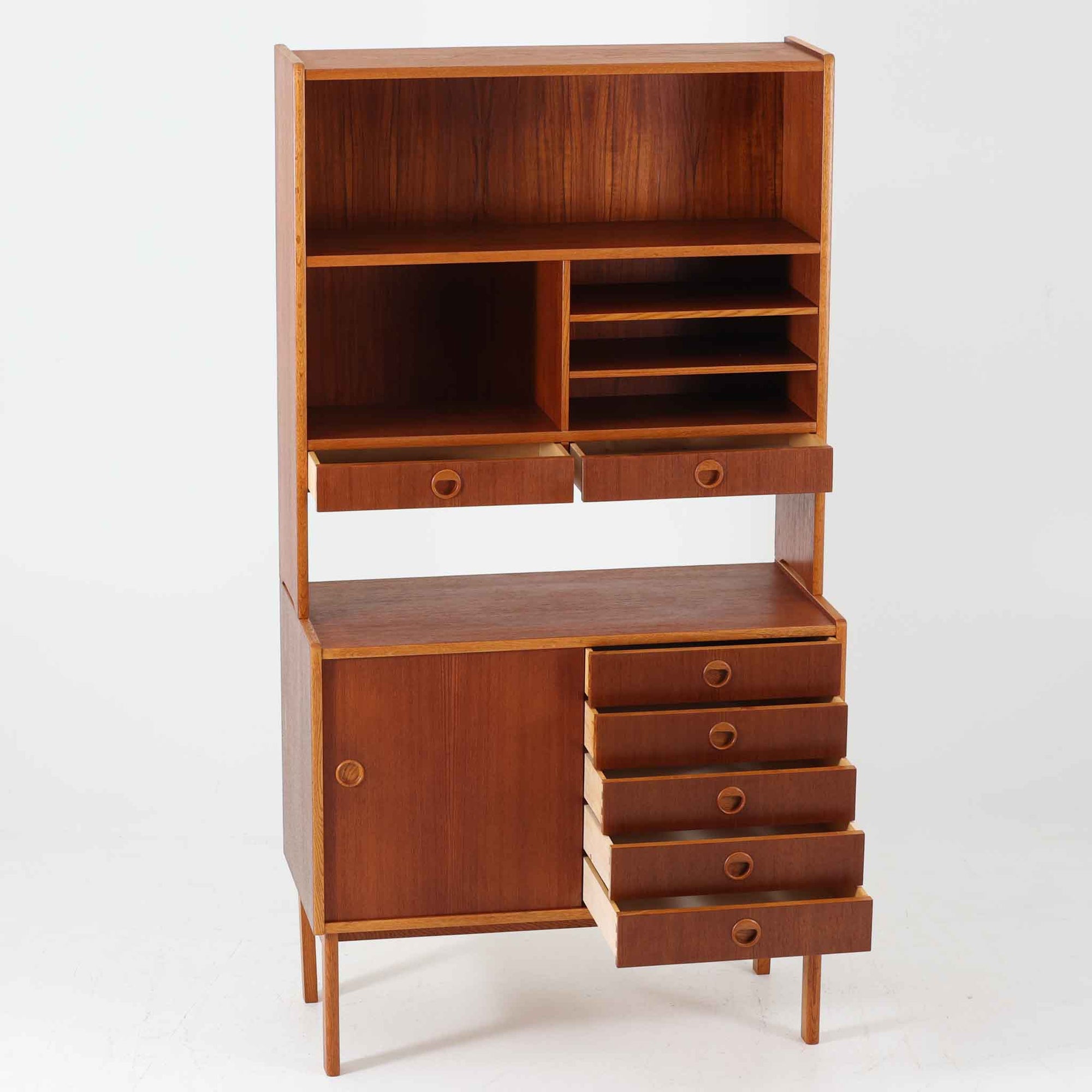 チーク材とオーク材を組み合わせたこちらのオープンシェルフは、スウェーデン製の北欧ビンテージ品で、幅85cmのコンパクトなサイズ感ながらも、引き出しや仕切り棚、スライド扉など多彩な収納機能を備えた実用的な一台です。温かみのある木の風合いと丸型の取手が、柔らかな印象を与えつつ、細部にまで配慮された職人技が感じられ、リビングや書斎の収納棚としてはもちろん、お気に入りの器や小物のディスプレイにも適しています。