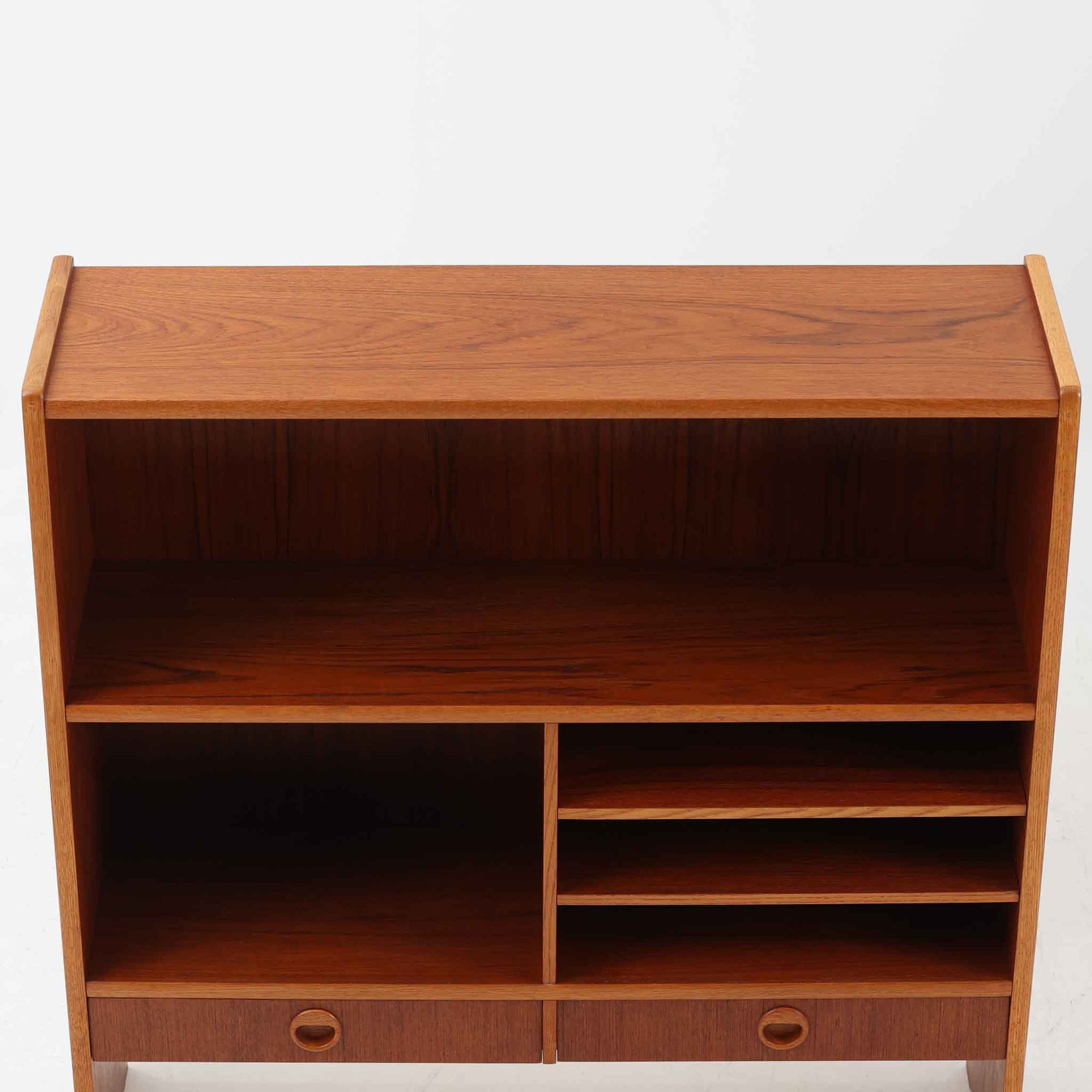 チーク材とオーク材を組み合わせたこちらのオープンシェルフは、スウェーデン製の北欧ビンテージ品で、幅85cmのコンパクトなサイズ感ながらも、引き出しや仕切り棚、スライド扉など多彩な収納機能を備えた実用的な一台です。温かみのある木の風合いと丸型の取手が、柔らかな印象を与えつつ、細部にまで配慮された職人技が感じられ、リビングや書斎の収納棚としてはもちろん、お気に入りの器や小物のディスプレイにも適しています。