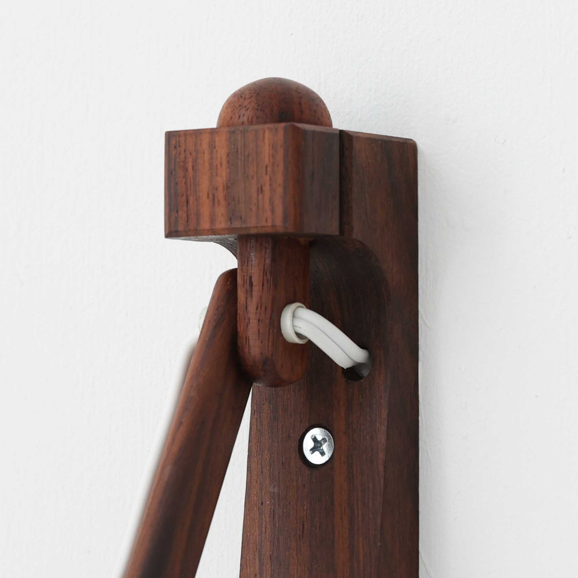 Erik Hansen（エリック・ハンセン）がデザインし、Le Klint（レ・クリント）より発表されたブラケットランプModel 332です。温かみのあるローズウッド材のアームと、職人技によるプリーツシェードの組み合わせが美しく、北欧らしい柔らかな光を演出します。アコーディオン式のアームは伸縮可能で、ベッドサイドやリビングの読書灯としても最適です。経年により味わいを増した木部とオリジナルシェードが、ビンテージならではの存在感を放ちます。ローズウッド材での展開はビンテージ品でのみ入手可能で、現行品には存在しない希少な一品です。