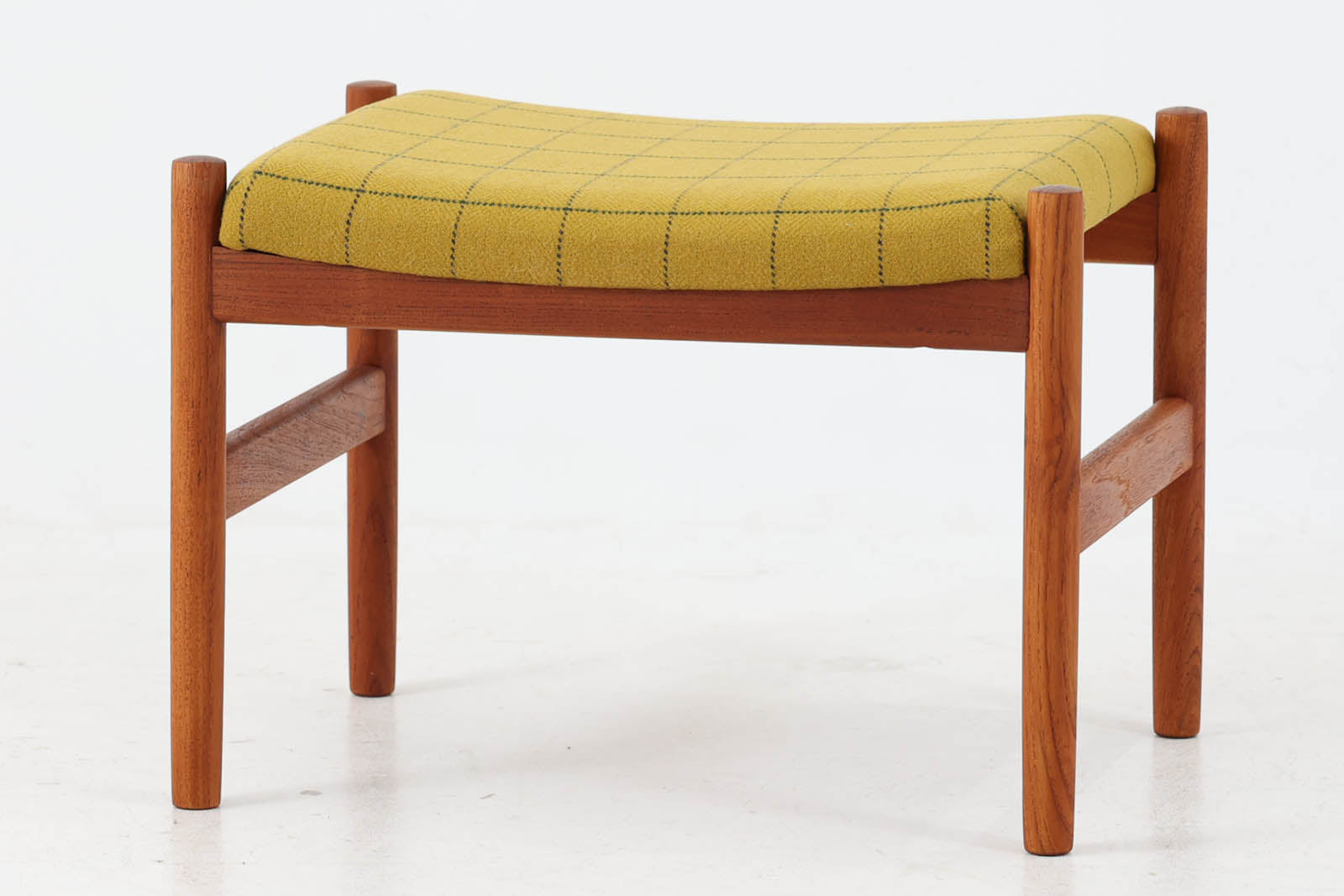 チーク材のフレームにイエロー系ファブリックを張ったスツールは、Spottrup Mobelfabrikによる北欧ビンテージ品で、緩やかなカーブを描く座面が身体にやさしくフィットし、オットマンとしてはもちろん玄関先やサイドチェア代わりにも重宝します。シンプルながらも細部まで丁寧に仕上げられたつくりからは、デンマーク家具らしい確かな品質と経年による風合いが感じられます。