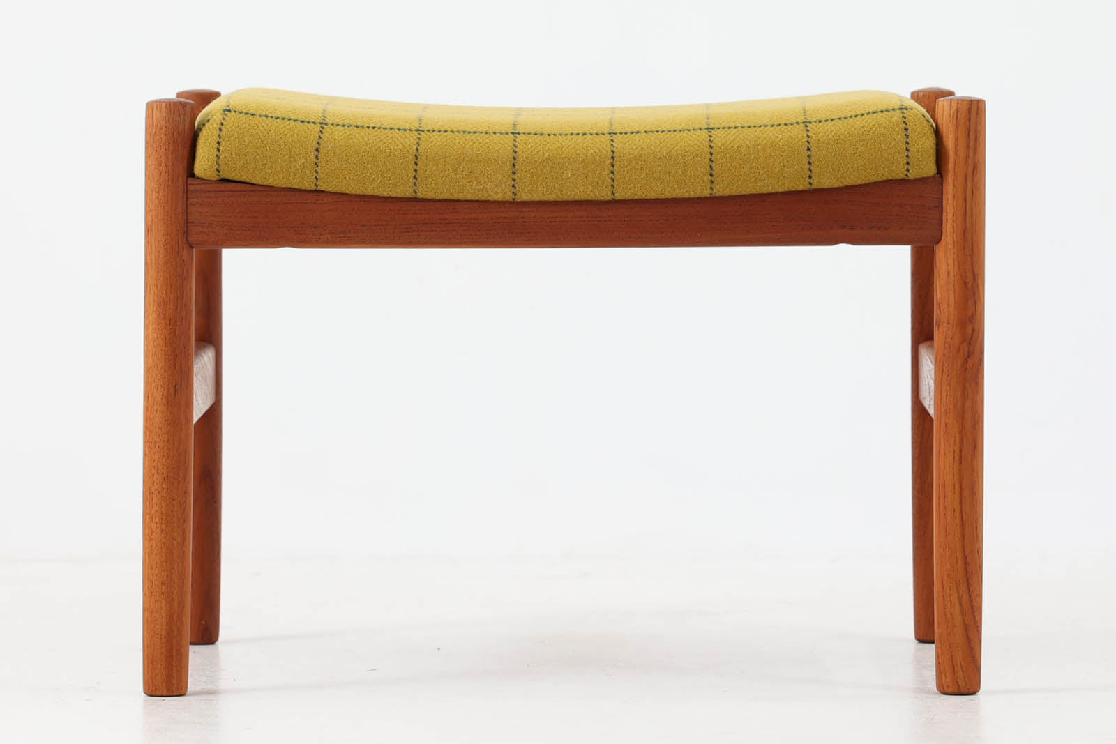 チーク材のフレームにイエロー系ファブリックを張ったスツールは、Spottrup Mobelfabrikによる北欧ビンテージ品で、緩やかなカーブを描く座面が身体にやさしくフィットし、オットマンとしてはもちろん玄関先やサイドチェア代わりにも重宝します。シンプルながらも細部まで丁寧に仕上げられたつくりからは、デンマーク家具らしい確かな品質と経年による風合いが感じられます。