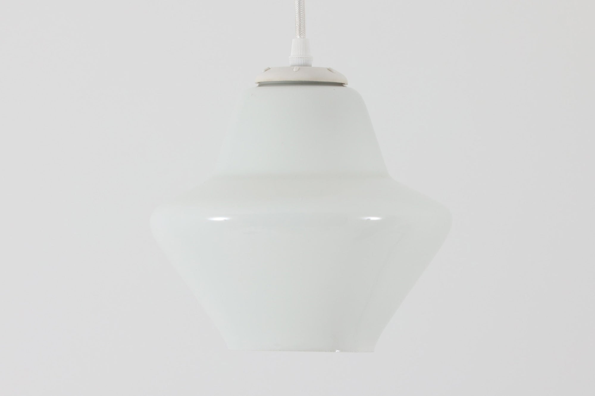 北欧より買い付けた乳白色ガラスのペンダントライトです。手拭きガラス特有の滑らかなラインが美しく、シンプルでありながらも存在感のあるデザインが魅力です。直径18cmのコンパクトなサイズ感は、ダイニングテーブルやリビングのアクセントとしてぴったりです。また、寝室や廊下、キッチンなどの狭いスペースにも適しています。光を柔らかく拡散し、落ち着いた雰囲気を演出します。