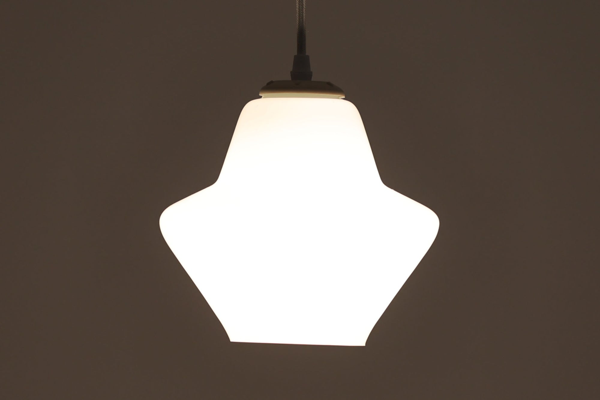 北欧より買い付けた乳白色ガラスのペンダントライトです。手拭きガラス特有の滑らかなラインが美しく、シンプルでありながらも存在感のあるデザインが魅力です。直径18cmのコンパクトなサイズ感は、ダイニングテーブルやリビングのアクセントとしてぴったりです。また、寝室や廊下、キッチンなどの狭いスペースにも適しています。光を柔らかく拡散し、落ち着いた雰囲気を演出します。