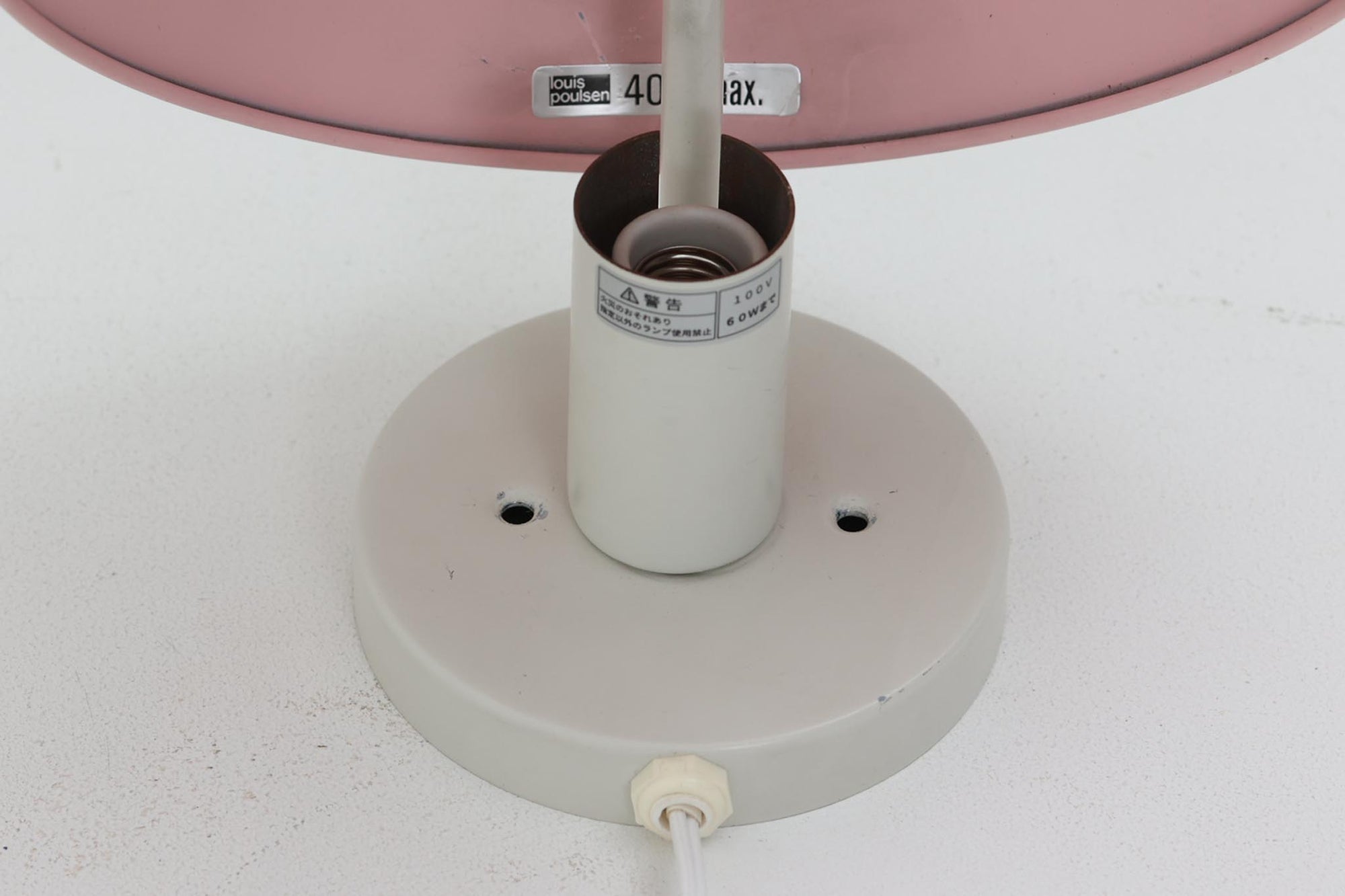 もともとへニングセンが自宅寝室のためにデザインし、1961年に発表したウォールライトで、温かみのある光を生むためシェード内面はローズ色に塗装されています。壁面でソフトな間接照明が得られ、広がり感のある空間をつくりだします。シェードが約60度可動するため、ベッドやソファーサイドの読書灯としても適しています。 