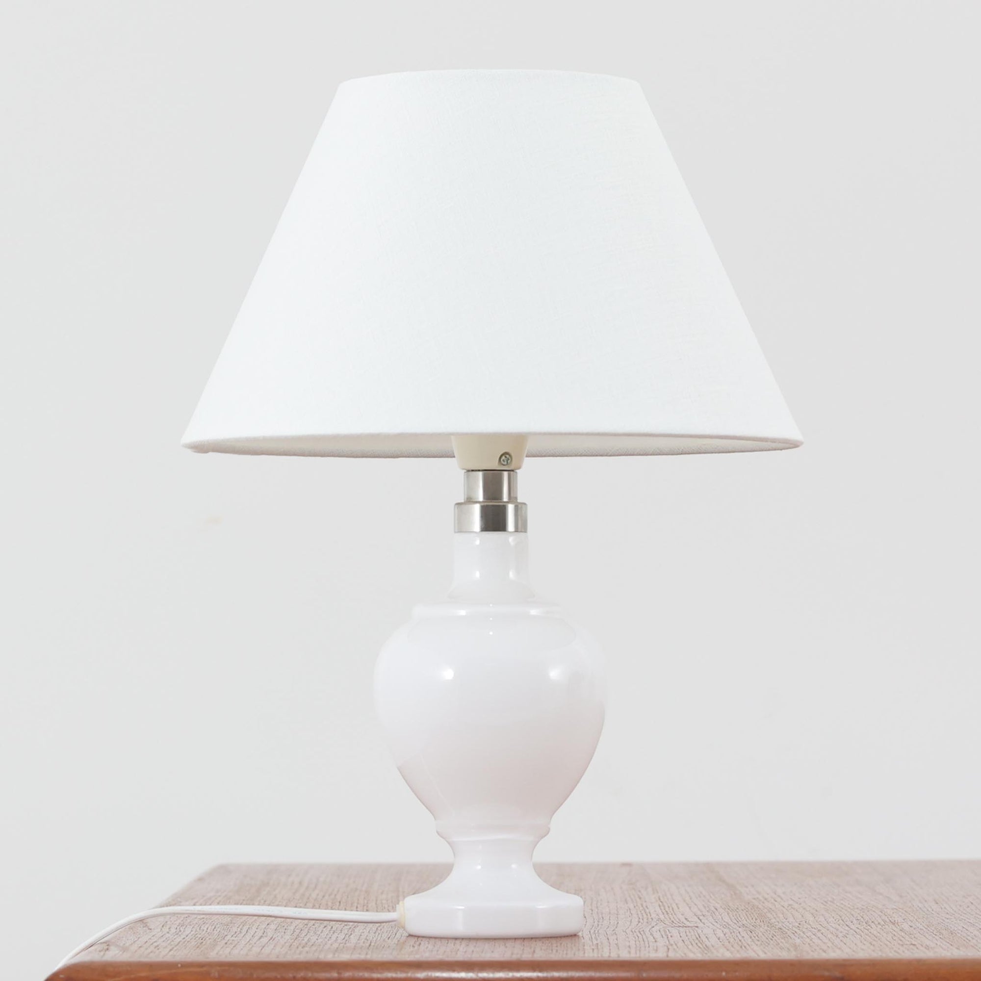 Anne Grethe von Halling-KochがRoyal Copenhagenより発表したモデル「Roma」のテーブルランプです。ガラスベースの柔らかな曲線が美しく、シェードにはリネンが用いられており、点灯時には温かみのある光が空間を優しく包み込みます。高さ34cmと程よいサイズ感で、ベッドサイドやリビングのアクセント照明としても最適です。デンマーク製ならではの洗練された造形と、経年を重ねたビンテージならではの趣が調和した一品です。