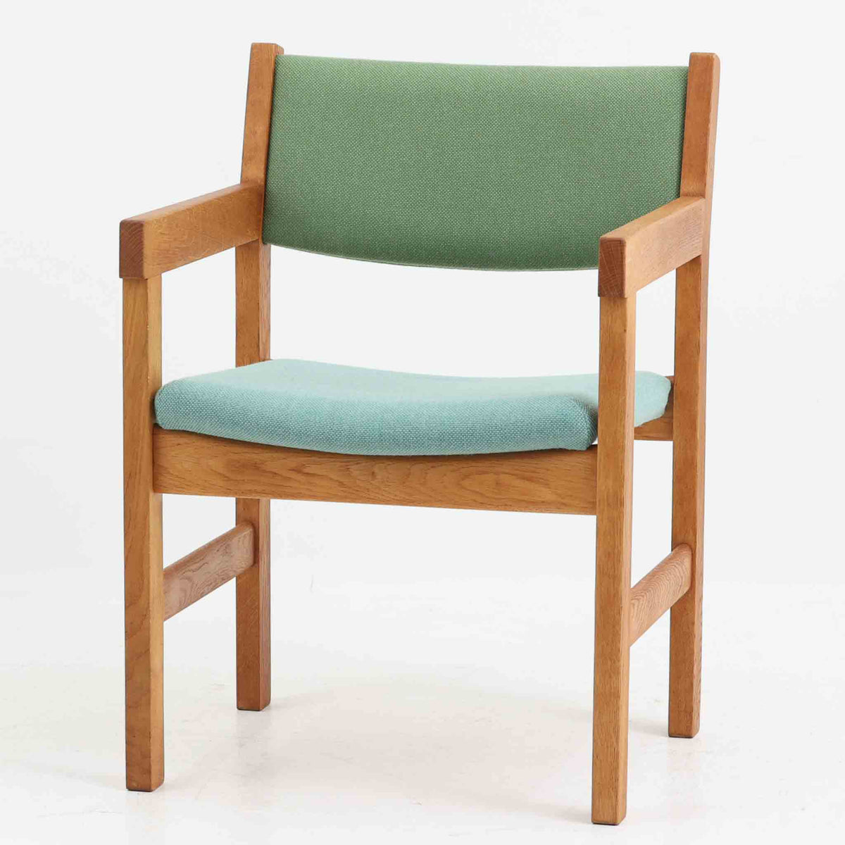 Hans J. Wegner（ハンス・J・ウェグナー）がデザインし、Getama（ゲタマ）が製造を手掛けたGE151アームチェアです。オーク材による直線的で端正なフレームに、ゆるやかにカーブした背もたれと座面を組み合わせた、軽快で機能的な佇まいが魅力。幅のあるアームは木の質感を存分に感じられ、長年の使用による風合いもビンテージならではの味わいです。ダイニングや書斎のほか、ゆったりと腰掛けるラウンジチェアとしても取り入れやすい一脚です。