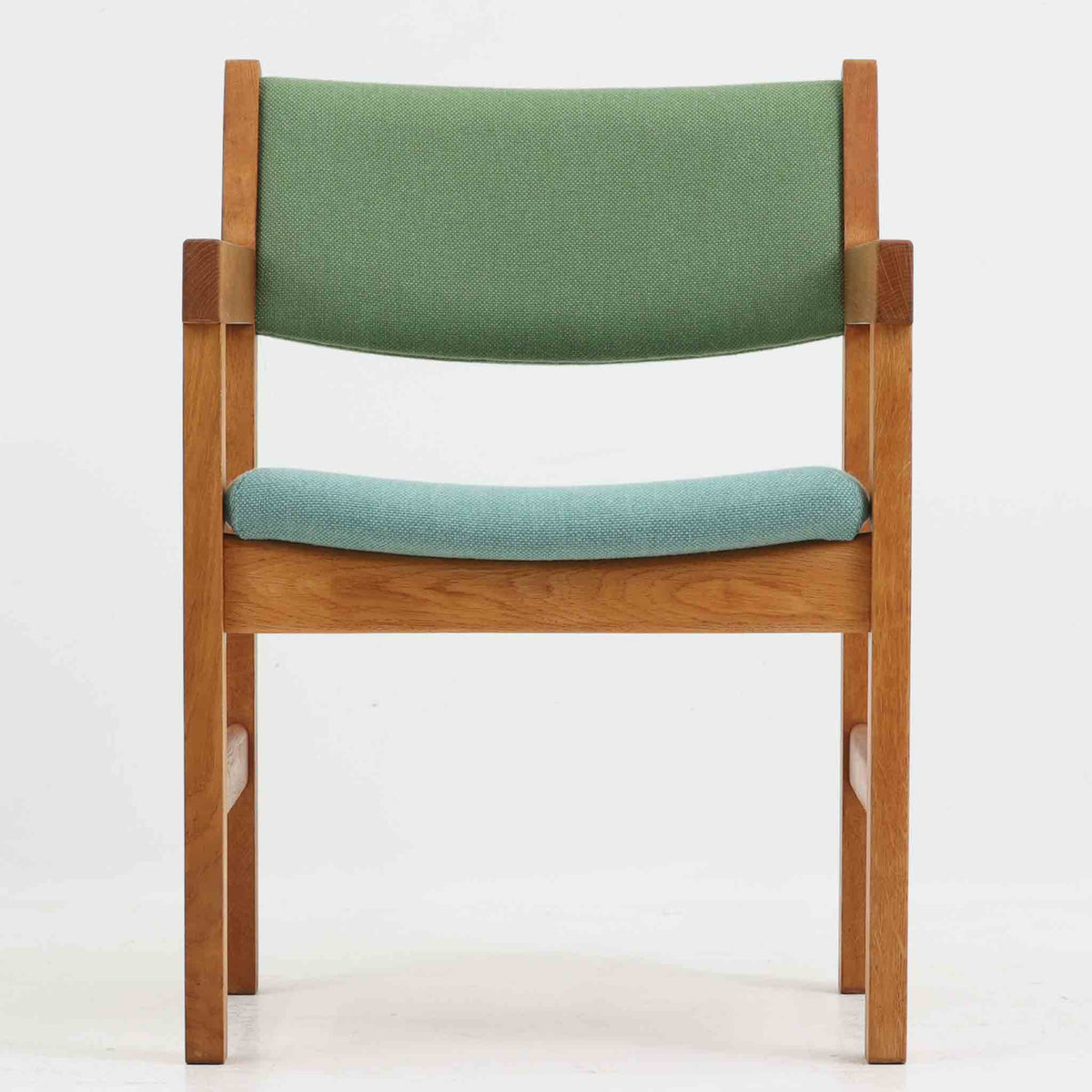 Hans J. Wegner（ハンス・J・ウェグナー）がデザインし、Getama（ゲタマ）が製造を手掛けたGE151アームチェアです。オーク材による直線的で端正なフレームに、ゆるやかにカーブした背もたれと座面を組み合わせた、軽快で機能的な佇まいが魅力。幅のあるアームは木の質感を存分に感じられ、長年の使用による風合いもビンテージならではの味わいです。ダイニングや書斎のほか、ゆったりと腰掛けるラウンジチェアとしても取り入れやすい一脚です。