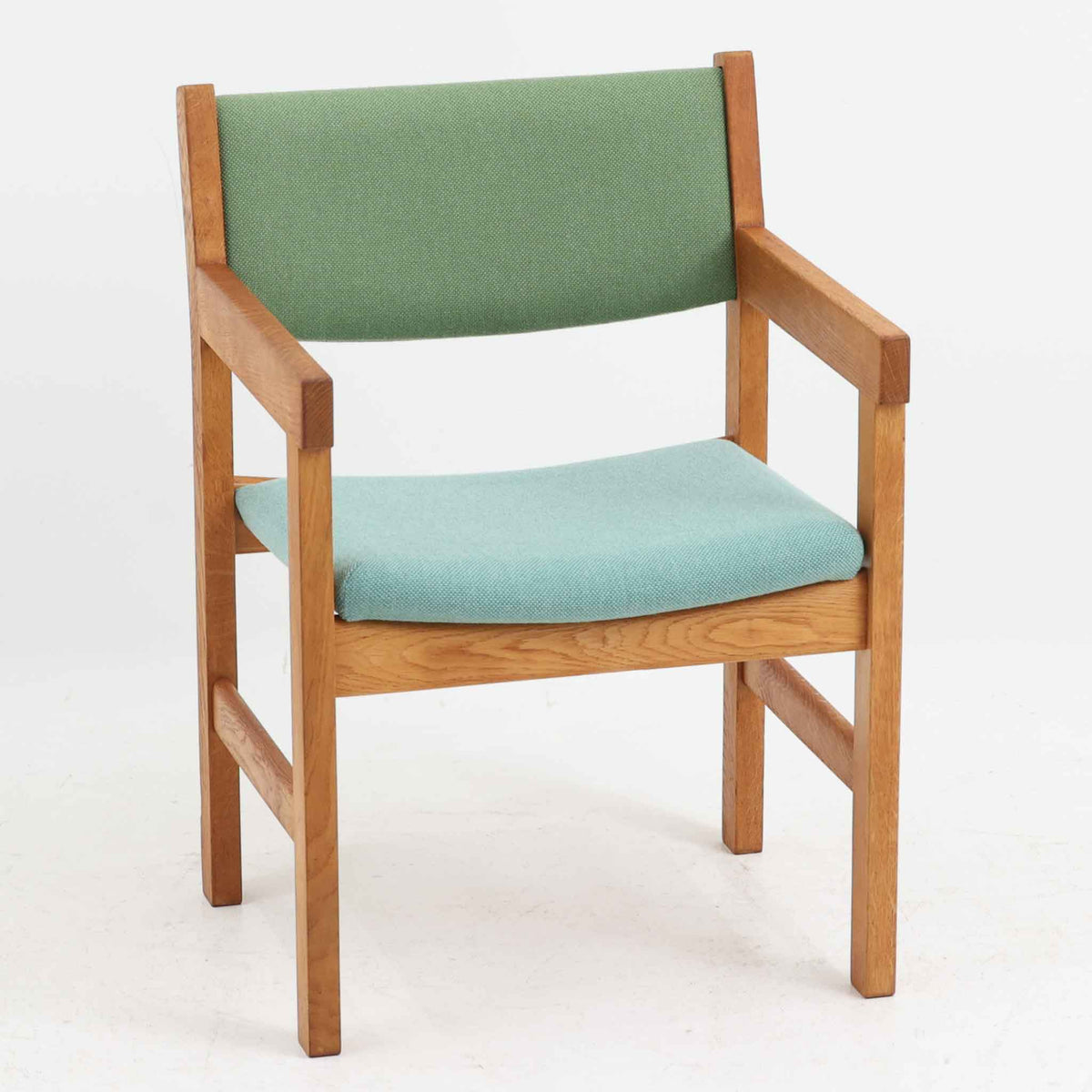 Hans J. Wegner（ハンス・J・ウェグナー）がデザインし、Getama（ゲタマ）が製造を手掛けたGE151アームチェアです。オーク材による直線的で端正なフレームに、ゆるやかにカーブした背もたれと座面を組み合わせた、軽快で機能的な佇まいが魅力。幅のあるアームは木の質感を存分に感じられ、長年の使用による風合いもビンテージならではの味わいです。ダイニングや書斎のほか、ゆったりと腰掛けるラウンジチェアとしても取り入れやすい一脚です。