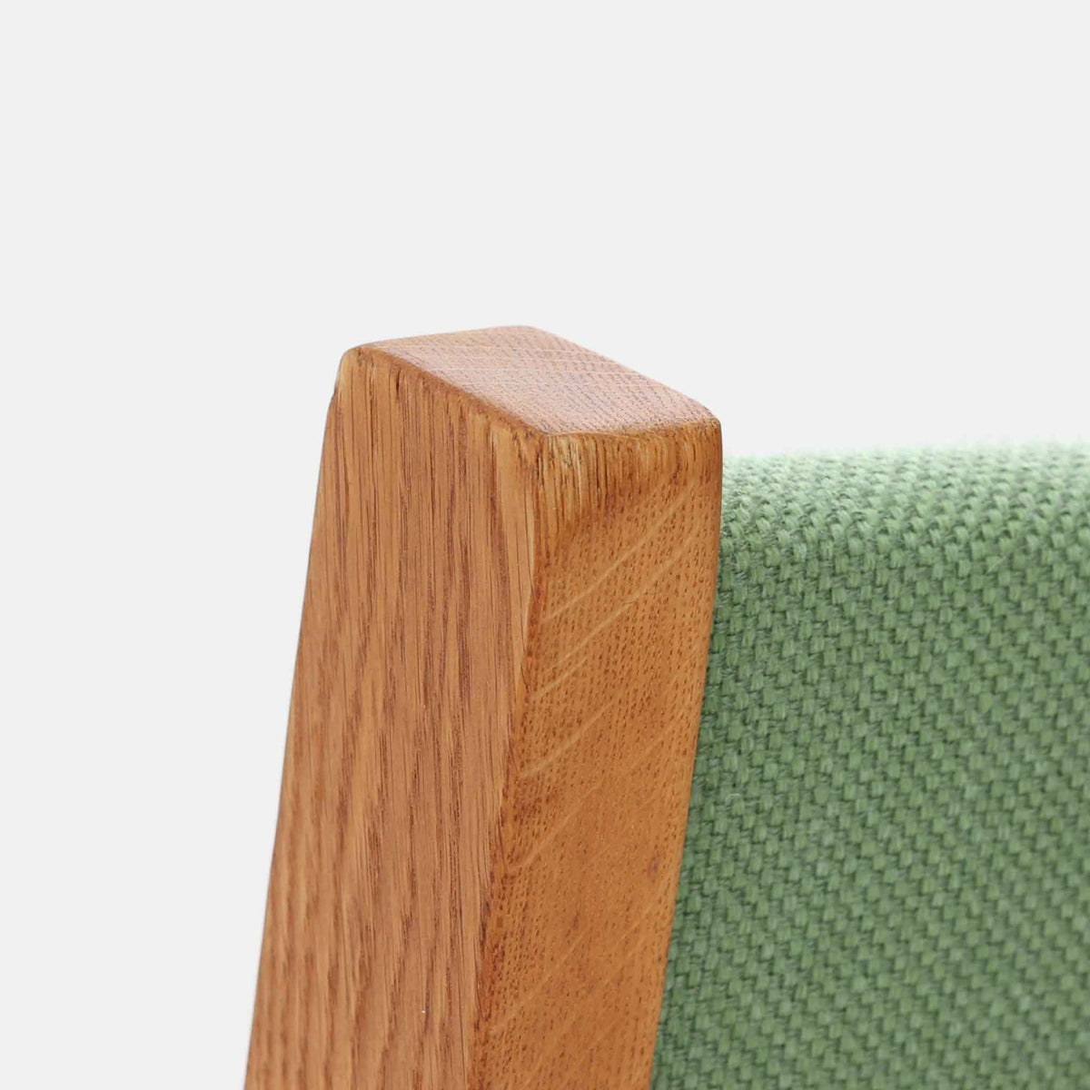 Hans J. Wegner（ハンス・J・ウェグナー）がデザインし、Getama（ゲタマ）が製造を手掛けたGE151アームチェアです。オーク材による直線的で端正なフレームに、ゆるやかにカーブした背もたれと座面を組み合わせた、軽快で機能的な佇まいが魅力。幅のあるアームは木の質感を存分に感じられ、長年の使用による風合いもビンテージならではの味わいです。ダイニングや書斎のほか、ゆったりと腰掛けるラウンジチェアとしても取り入れやすい一脚です。