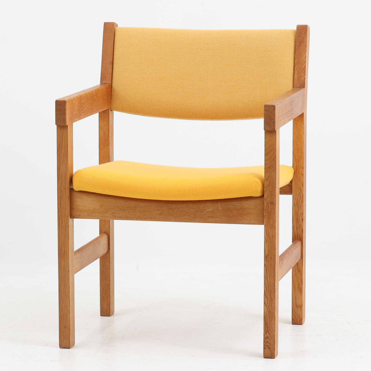 Hans J. Wegner（ハンス・J・ウェグナー）がデザインし、Getama（ゲタマ）が製造を手掛けたGE151アームチェアです。オーク材による直線的で端正なフレームに、ゆるやかにカーブした背もたれと座面を組み合わせた、軽快で機能的な佇まいが魅力。幅のあるアームは木の質感を存分に感じられ、長年の使用による風合いもビンテージならではの味わいです。ダイニングや書斎のほか、ゆったりと腰掛けるラウンジチェアとしても取り入れやすい一脚です。