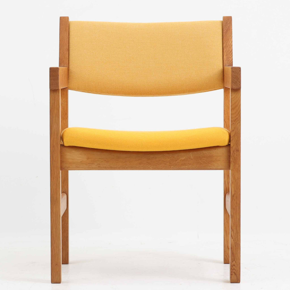 Hans J. Wegner（ハンス・J・ウェグナー）がデザインし、Getama（ゲタマ）が製造を手掛けたGE151アームチェアです。オーク材による直線的で端正なフレームに、ゆるやかにカーブした背もたれと座面を組み合わせた、軽快で機能的な佇まいが魅力。幅のあるアームは木の質感を存分に感じられ、長年の使用による風合いもビンテージならではの味わいです。ダイニングや書斎のほか、ゆったりと腰掛けるラウンジチェアとしても取り入れやすい一脚です。