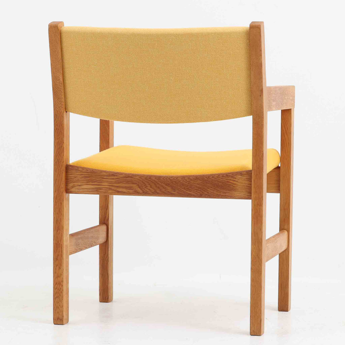 Hans J. Wegner（ハンス・J・ウェグナー）がデザインし、Getama（ゲタマ）が製造を手掛けたGE151アームチェアです。オーク材による直線的で端正なフレームに、ゆるやかにカーブした背もたれと座面を組み合わせた、軽快で機能的な佇まいが魅力。幅のあるアームは木の質感を存分に感じられ、長年の使用による風合いもビンテージならではの味わいです。ダイニングや書斎のほか、ゆったりと腰掛けるラウンジチェアとしても取り入れやすい一脚です。