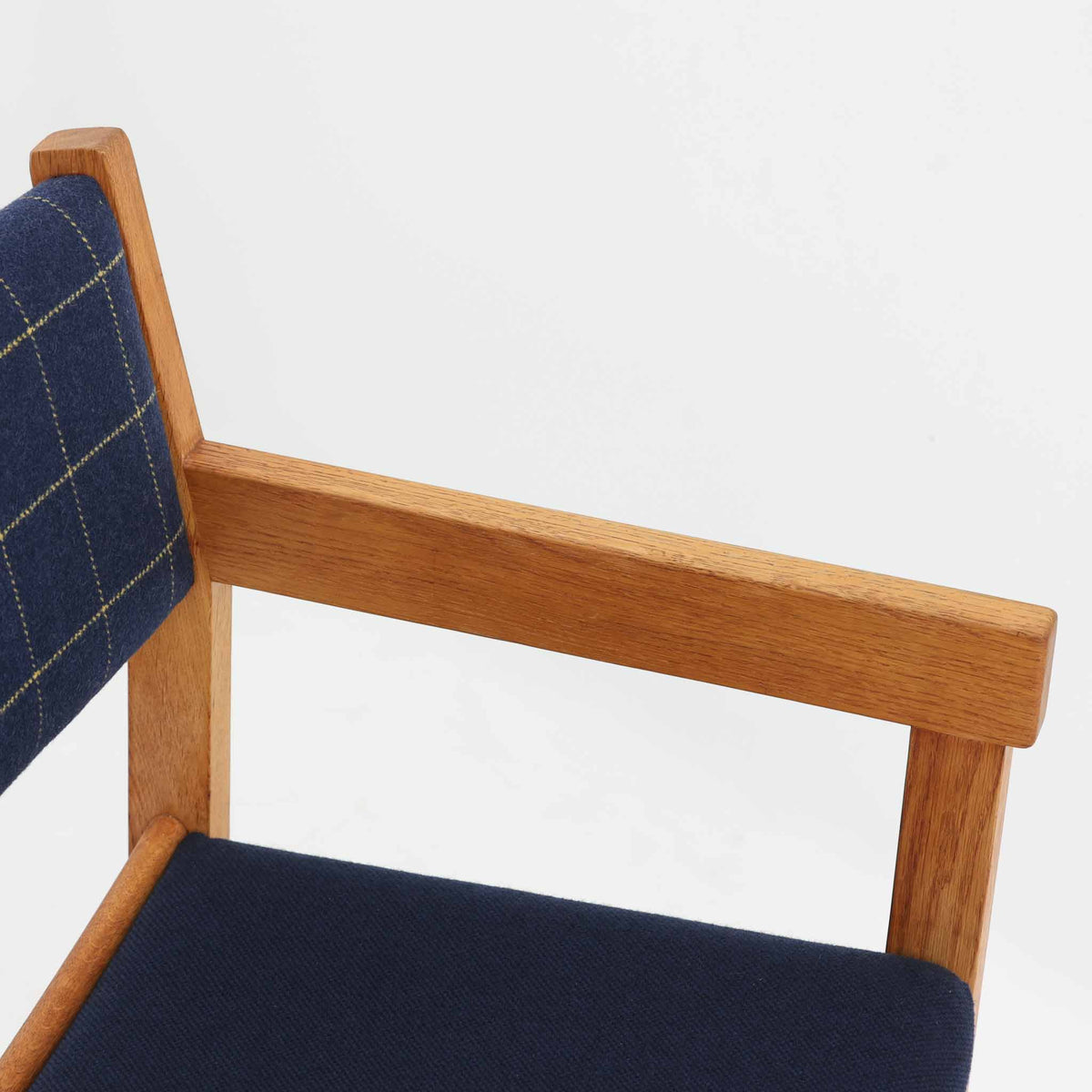 Hans J. Wegner（ハンス・J・ウェグナー）がデザインし、Getama（ゲタマ）が製造を手掛けたGE151アームチェアです。オーク材による直線的で端正なフレームに、ゆるやかにカーブした背もたれと座面を組み合わせた、軽快で機能的な佇まいが魅力。幅のあるアームは木の質感を存分に感じられ、長年の使用による風合いもビンテージならではの味わいです。ダイニングや書斎のほか、ゆったりと腰掛けるラウンジチェアとしても取り入れやすい一脚です。