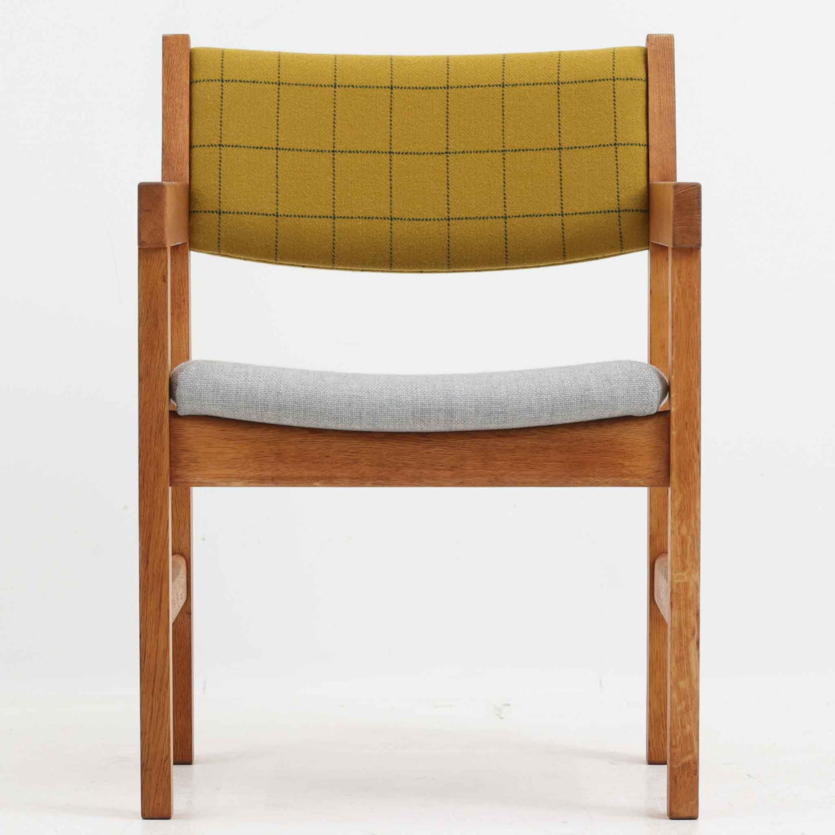 Hans J. Wegner（ハンス・J・ウェグナー）がデザインし、Getama（ゲタマ）が製造を手掛けたGE151アームチェアです。オーク材による直線的で端正なフレームに、ゆるやかにカーブした背もたれと座面を組み合わせた、軽快で機能的な佇まいが魅力。幅のあるアームは木の質感を存分に感じられ、長年の使用による風合いもビンテージならではの味わいです。ダイニングや書斎のほか、ゆったりと腰掛けるラウンジチェアとしても取り入れやすい一脚です。