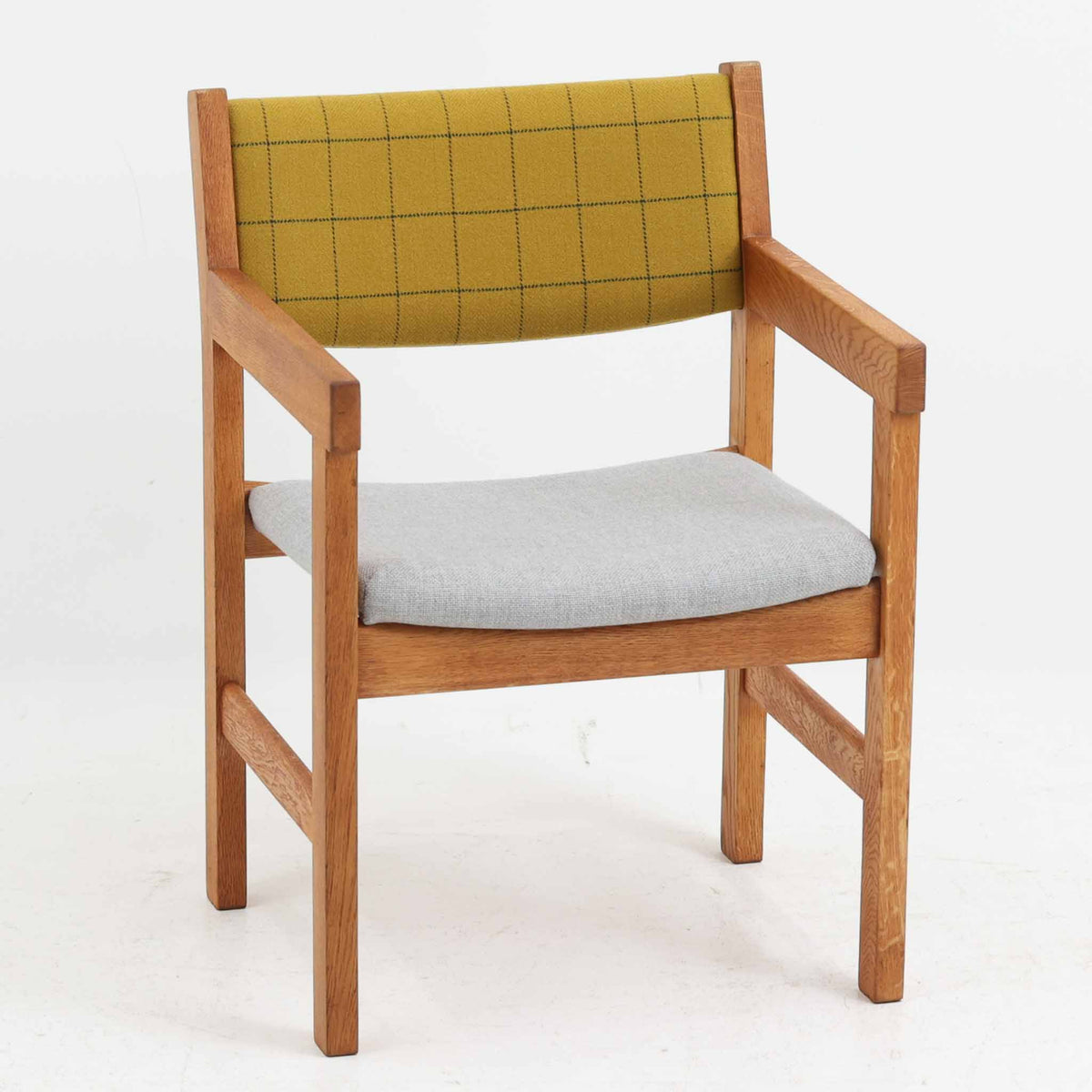Hans J. Wegner（ハンス・J・ウェグナー）がデザインし、Getama（ゲタマ）が製造を手掛けたGE151アームチェアです。オーク材による直線的で端正なフレームに、ゆるやかにカーブした背もたれと座面を組み合わせた、軽快で機能的な佇まいが魅力。幅のあるアームは木の質感を存分に感じられ、長年の使用による風合いもビンテージならではの味わいです。ダイニングや書斎のほか、ゆったりと腰掛けるラウンジチェアとしても取り入れやすい一脚です。
