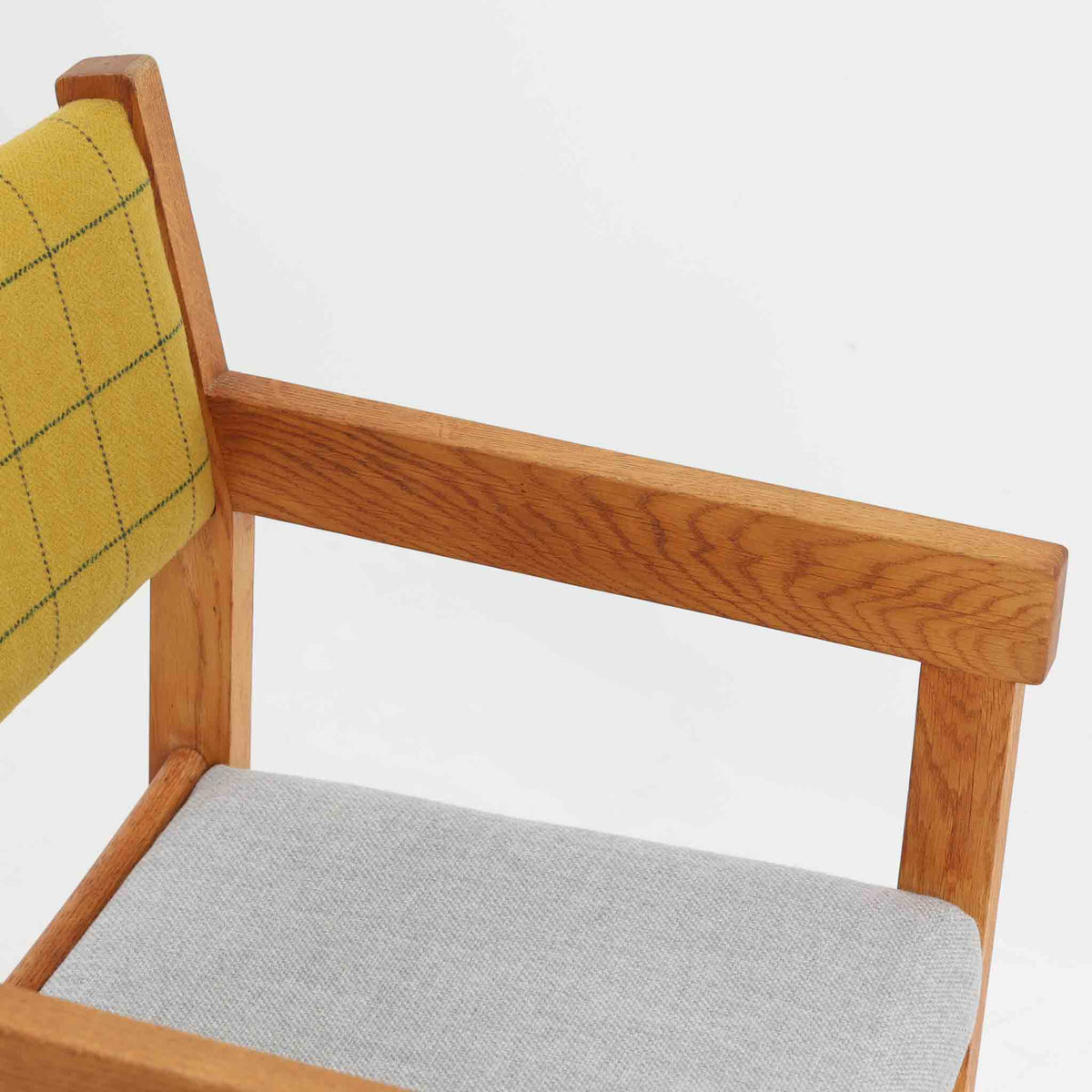 Hans J. Wegner（ハンス・J・ウェグナー）がデザインし、Getama（ゲタマ）が製造を手掛けたGE151アームチェアです。オーク材による直線的で端正なフレームに、ゆるやかにカーブした背もたれと座面を組み合わせた、軽快で機能的な佇まいが魅力。幅のあるアームは木の質感を存分に感じられ、長年の使用による風合いもビンテージならではの味わいです。ダイニングや書斎のほか、ゆったりと腰掛けるラウンジチェアとしても取り入れやすい一脚です。