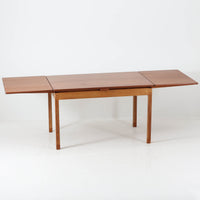 Ejner Larsen & Aksel Bender Madsenが手掛け、Naestved Mobelfabrikで製作されたエクステンションダイニングテーブルは、チーク材の天板とオーク材の脚部を組み合わせた北欧ビンテージらしい上質な佇まいが魅力です。直線的で端正なフォルムの中に、天板縁の丁寧な面取りや幕板の滑らかな造形など、当時の高い職人技が随所に感じられます。幅120cmから最大230cmまで伸長可能な構造により、日常使いから来客時まで柔軟に対応でき、空間や人数に合わせた使い方が可能です。経年変化によって深みを増した木肌の表情が、長く愛用されてきたビンテージならではの存在感を放ち、ダイニングの主役として落ち着きと品格を添えてくれる一台です。脚先には床へのダメージや汚れを防ぐためにチーク材がジョイントされており、実用性を考慮した当時の設計思想がうかがえます。また、裏面には「SKM」の刻印が確認でき、スウェーデン軍（Svenska KrigsMakten）の備品として使用されていたことを示す、背景のある希少な個体です。