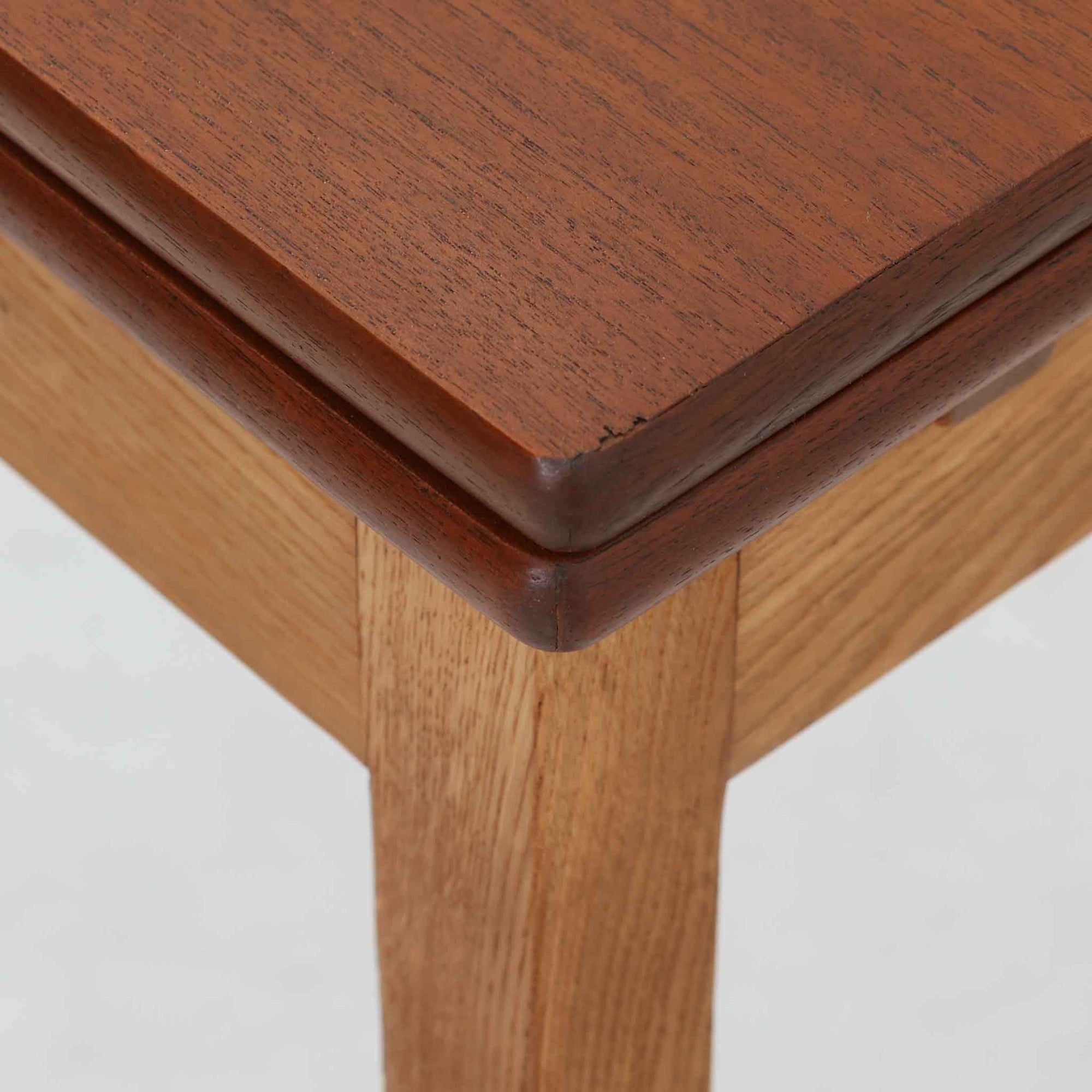 Ejner Larsen &amp; Aksel Bender Madsenが手掛け、Naestved Mobelfabrikで製作されたエクステンションダイニングテーブルは、チーク材の天板とオーク材の脚部を組み合わせた北欧ビンテージらしい上質な佇まいが魅力です。直線的で端正なフォルムの中に、天板縁の丁寧な面取りや幕板の滑らかな造形など、当時の高い職人技が随所に感じられます。幅120cmから最大230cmまで伸長可能な構造により、日常使いから来客時まで柔軟に対応でき、空間や人数に合わせた使い方が可能です。経年変化によって深みを増した木肌の表情が、長く愛用されてきたビンテージならではの存在感を放ち、ダイニングの主役として落ち着きと品格を添えてくれる一台です。脚先には床へのダメージや汚れを防ぐためにチーク材がジョイントされており、実用性を考慮した当時の設計思想がうかがえます。また、裏面には「SKM」の刻印が確認でき、スウェーデン軍（Svenska KrigsMakten）の備品として使用されていたことを示す、背景のある希少な個体です。