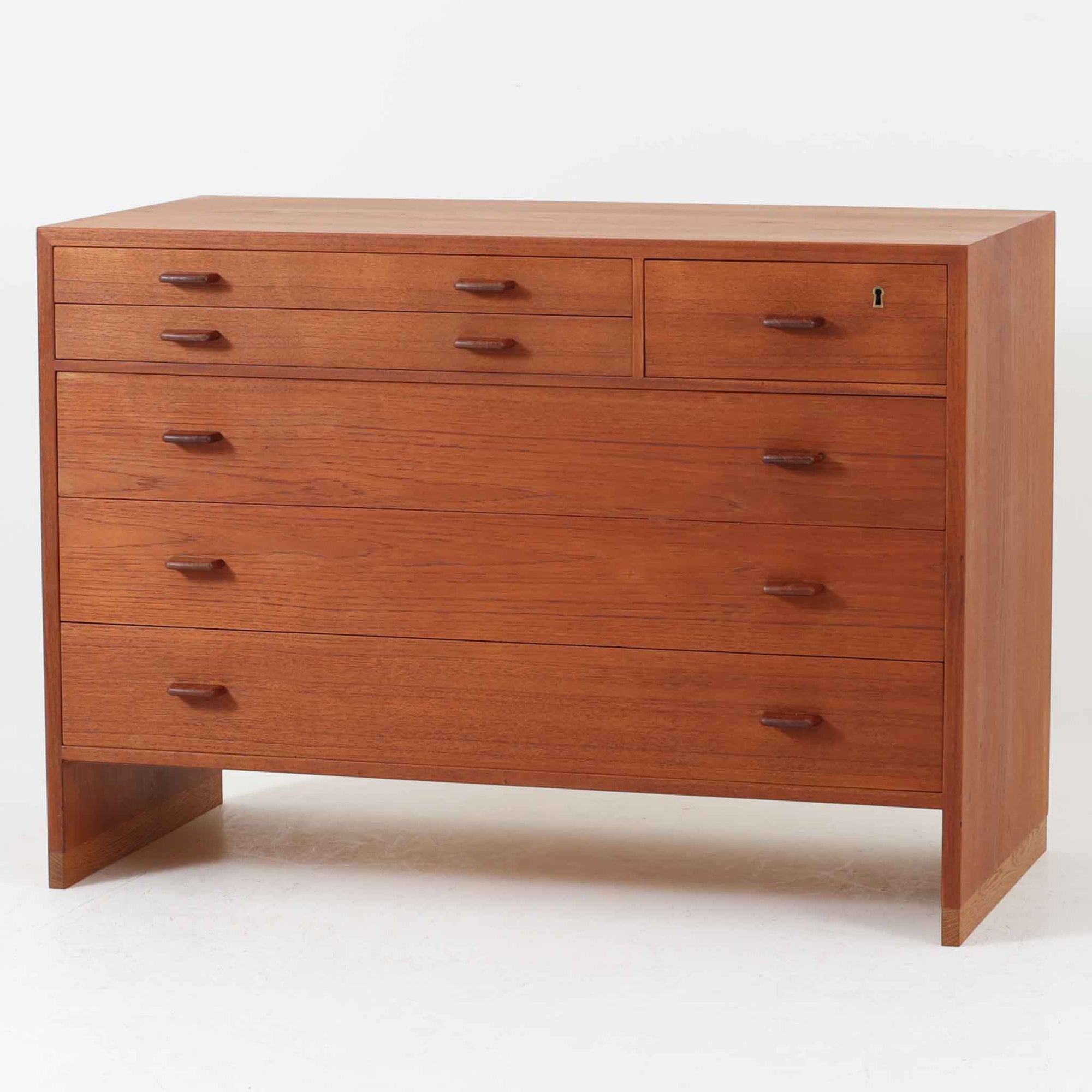 Hans J. Wegnerが手掛けたこちらの多段チェストは、Ry Mobler社によって1962年に製造されたもので、チーク材とオーク材の美しいコントラストが印象的な一台です。チーク材仕様のモデルは現存数が少なく、希少です。端正なフォルムと落ち着いた木肌は、寝室やリビングに上質な温もりをもたらします。引き出し内部にはフェルトが敷かれ、最上段には鍵付きの収納も備わっており、細部にまでこだわった設計が魅力です。※写真には写っておりませんが、鍵が1点付属いたします。実用性と美しさを兼ね備えた、北欧ビンテージらしい逸品です。