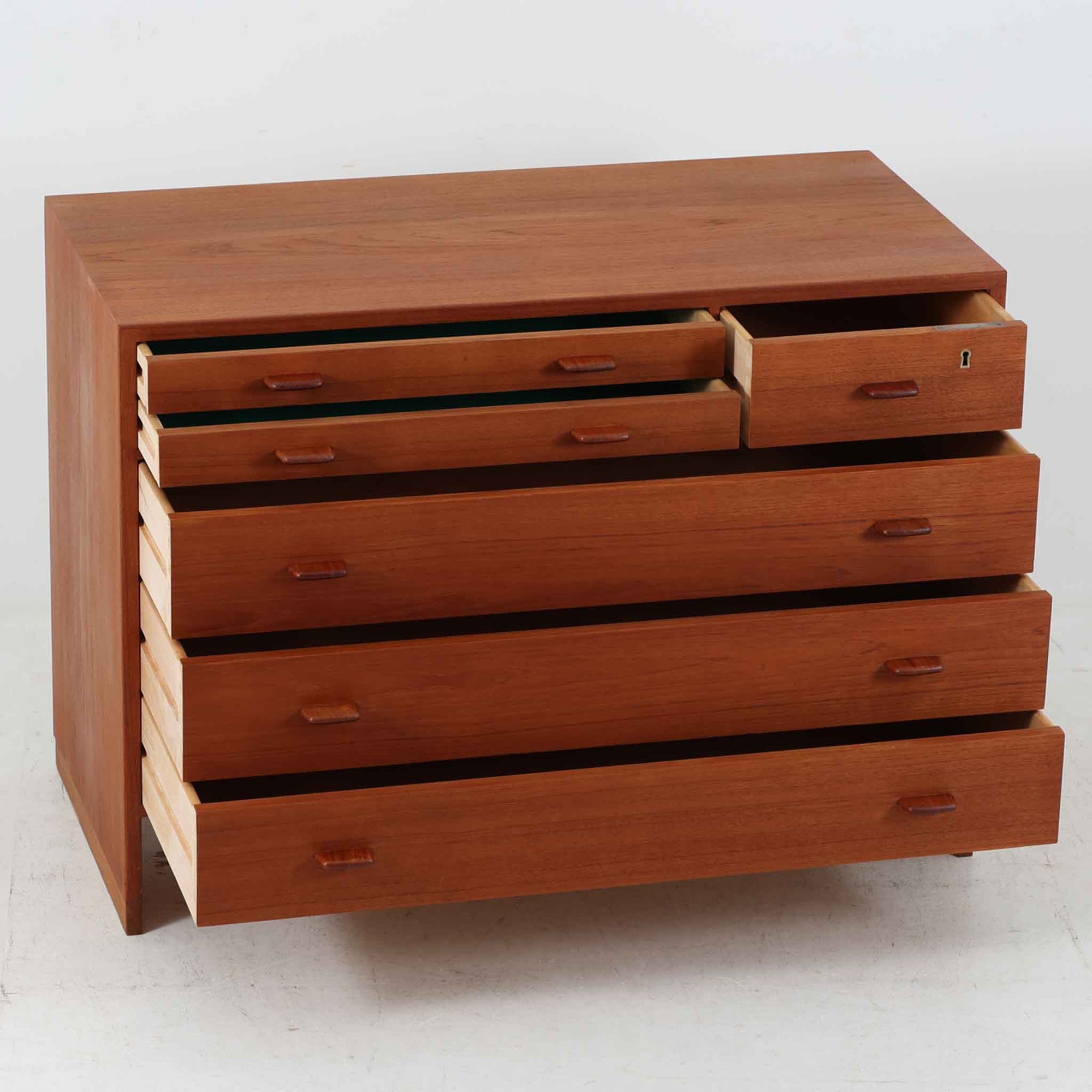 Hans J. Wegnerが手掛けたこちらの多段チェストは、Ry Mobler社によって1962年に製造されたもので、チーク材とオーク材の美しいコントラストが印象的な一台です。チーク材仕様のモデルは現存数が少なく、希少です。端正なフォルムと落ち着いた木肌は、寝室やリビングに上質な温もりをもたらします。引き出し内部にはフェルトが敷かれ、最上段には鍵付きの収納も備わっており、細部にまでこだわった設計が魅力です。※写真には写っておりませんが、鍵が1点付属いたします。実用性と美しさを兼ね備えた、北欧ビンテージらしい逸品です。