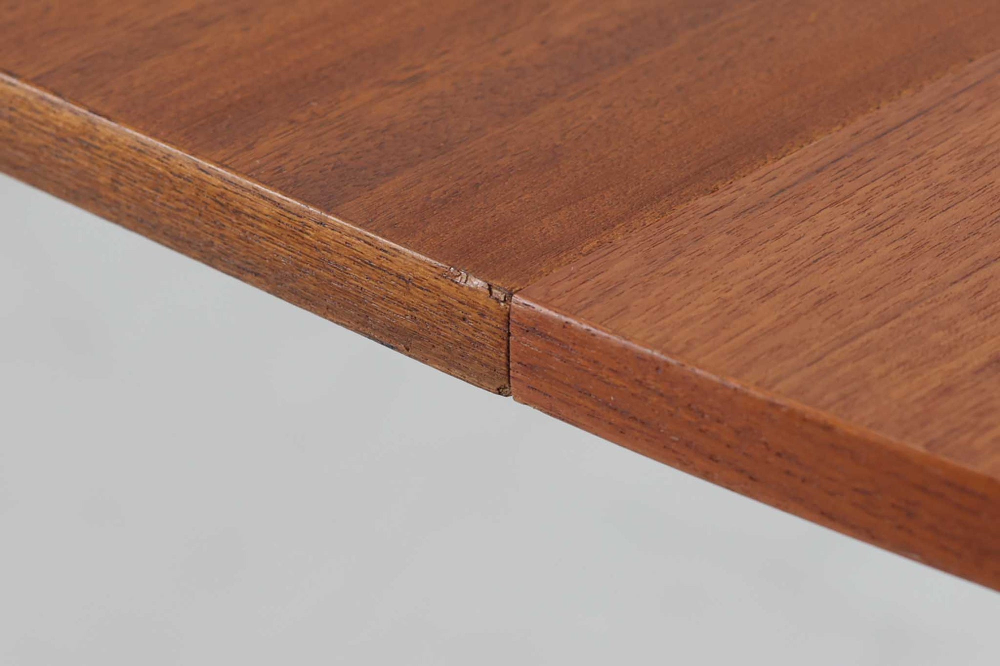 こちらはスウェーデンで買い付けたエクステンションダイニングテーブルです。天板は、珍しいラウンドスクエアの形状を採用しており、柔らかな印象と洗練されたデザインが魅力です。脚部は左右に開く構造で安定感があり、幕板は中央部分に向かってカットされているため、椅子の出し入れや座り心地にも配慮されています。また、来客時には付属の拡張板を使用することで、天板を簡単に広げられ、大人数での食事にも対応可能です。使い手の利便性を追求した設計が光る一品です。素材には、良質なチーク材とオーク材を使用しており、木目の美しさや温かみを感じられます。北欧家具ならではの高いデザイン性と実用性を兼ね備えたダイニングテーブルをぜひお楽しみください。