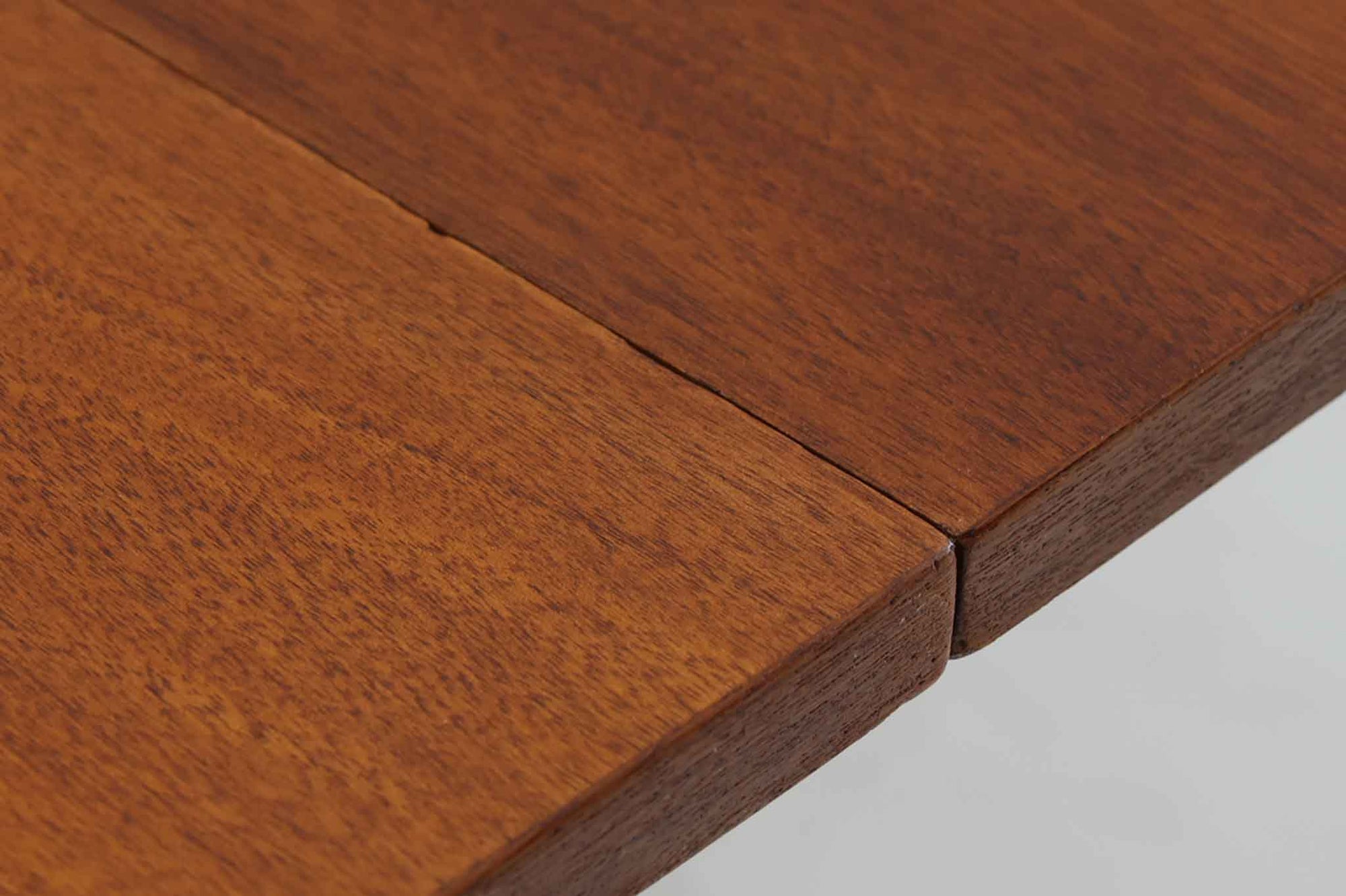 こちらはスウェーデンで買い付けたエクステンションダイニングテーブルです。天板は、珍しいラウンドスクエアの形状を採用しており、柔らかな印象と洗練されたデザインが魅力です。脚部は左右に開く構造で安定感があり、幕板は中央部分に向かってカットされているため、椅子の出し入れや座り心地にも配慮されています。また、来客時には付属の拡張板を使用することで、天板を簡単に広げられ、大人数での食事にも対応可能です。使い手の利便性を追求した設計が光る一品です。素材には、良質なチーク材とオーク材を使用しており、木目の美しさや温かみを感じられます。北欧家具ならではの高いデザイン性と実用性を兼ね備えたダイニングテーブルをぜひお楽しみください。