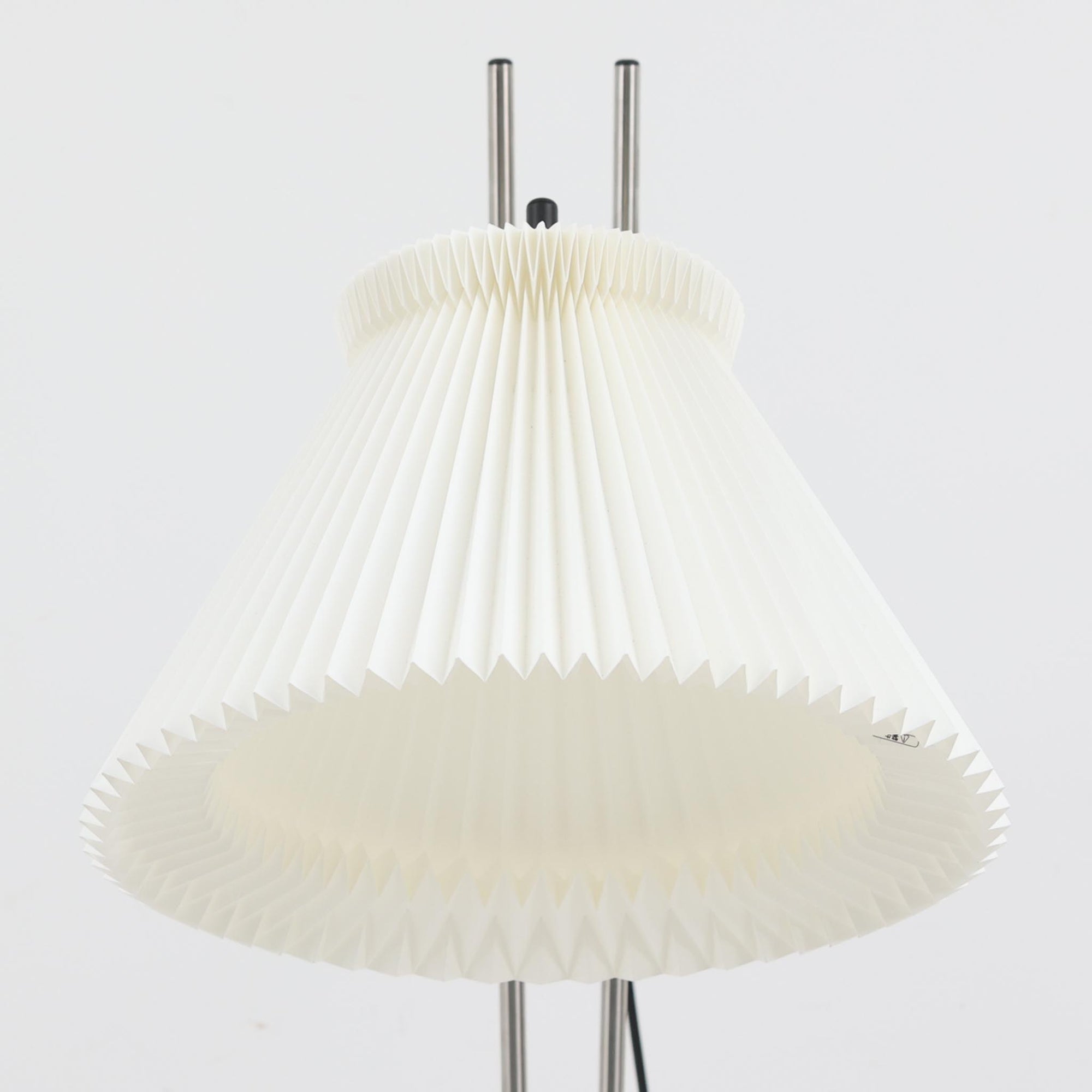 Christian Hvidtによってデザインされ、Le Klint社から発表されたフロアランプModel 323です。スチール製のシャープなフレームに、手作業で折り込まれたプリーツシェードを組み合わせた構成が特徴で、北欧デザインらしいシンプルかつ機能的な美しさを備えています。高さ135cmのバランスの良いサイズ感で、リビングや書斎に柔らかな光を届けます。角度調整可能なアームは使い勝手に優れ、読書灯や間接照明としても重宝するビンテージ品です。