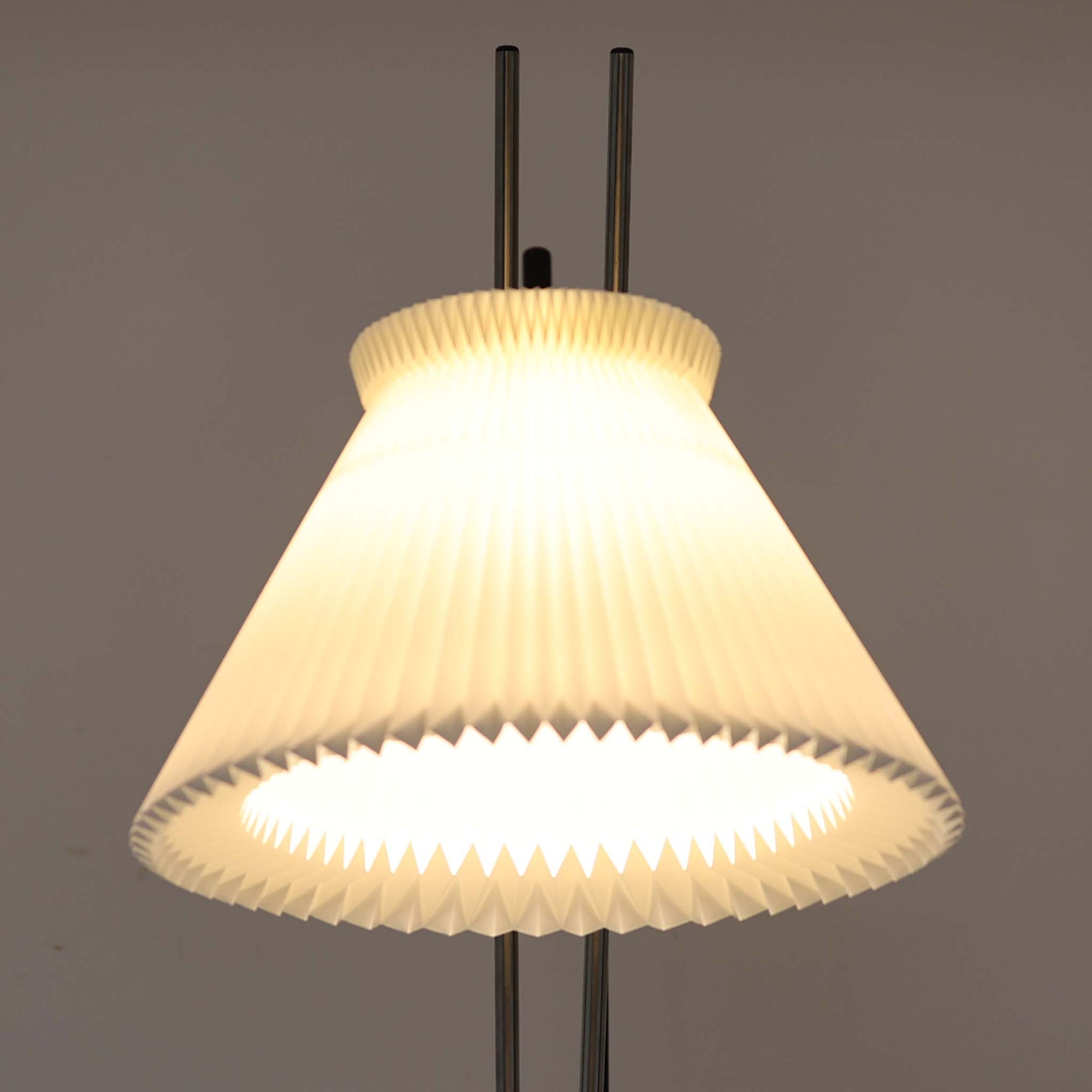 Christian Hvidtによってデザインされ、Le Klint社から発表されたフロアランプModel 323です。スチール製のシャープなフレームに、手作業で折り込まれたプリーツシェードを組み合わせた構成が特徴で、北欧デザインらしいシンプルかつ機能的な美しさを備えています。高さ135cmのバランスの良いサイズ感で、リビングや書斎に柔らかな光を届けます。角度調整可能なアームは使い勝手に優れ、読書灯や間接照明としても重宝するビンテージ品です。