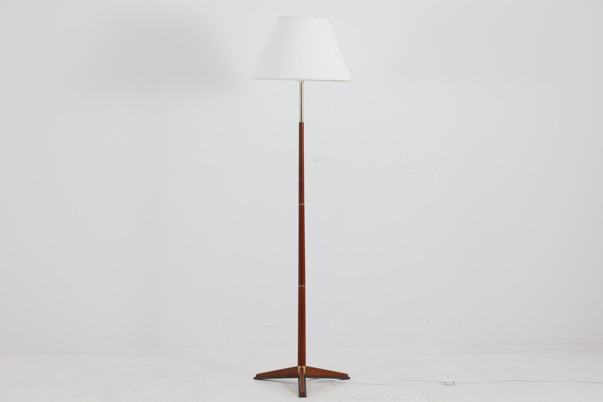 北欧から買い付けたデンマーク製のフロアランプです。贅沢にチーク無垢材が使用されたフレームと、ゴールド色の金属がアクセントとして施されています。支柱は上に向かって細くなり、浮遊感のあるデザインで、非常にすっきりとした印象を与えます。ビンテージならではの3本脚が、デザインに一層の魅力を添えています。