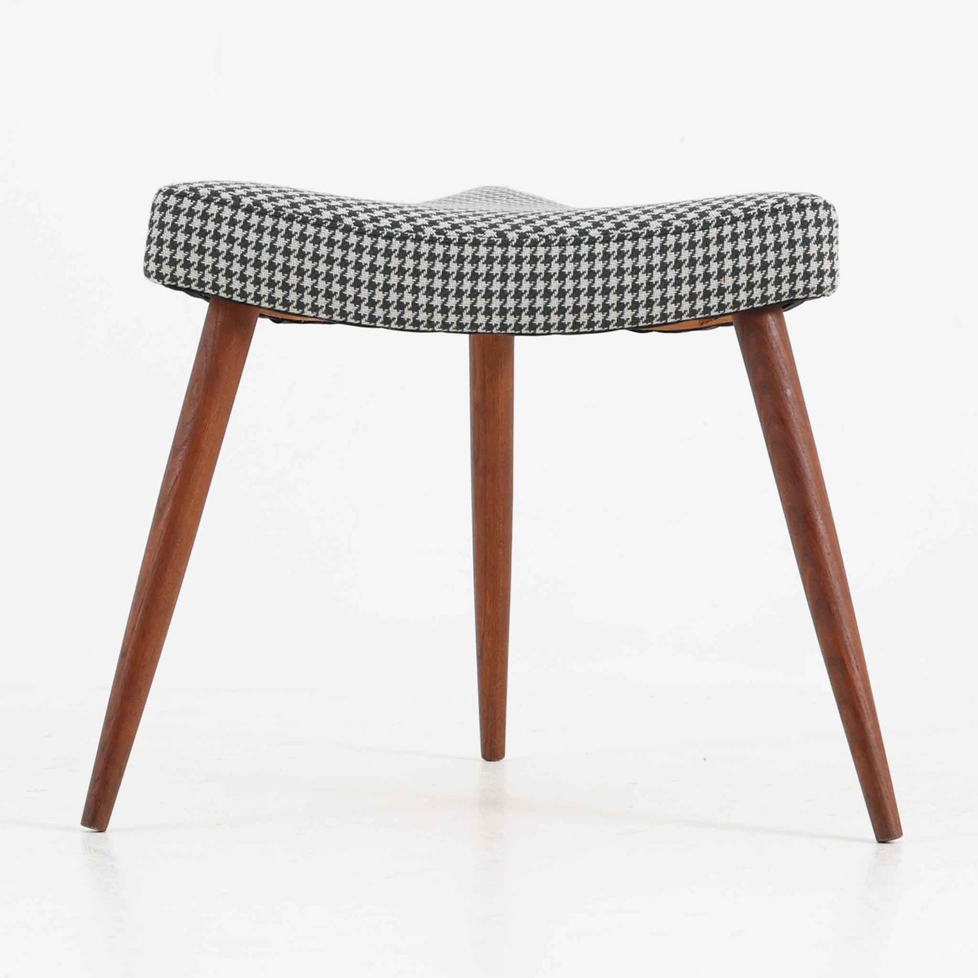 デンマーク製スツールです。3本脚の軽やかなフォルムに、チーク材の温もりが感じられる北欧ビンテージらしい佇まいが魅力です。三角形の座面は座り心地を考慮した絶妙な曲面で構成され、張地は千鳥格子柄のファブリックで仕上げました。玄関や寝室の補助椅子としてはもちろん、オットマンとしても活躍します。経年により深みを増したチーク材の脚が空間に上品な印象を与える一脚です。
